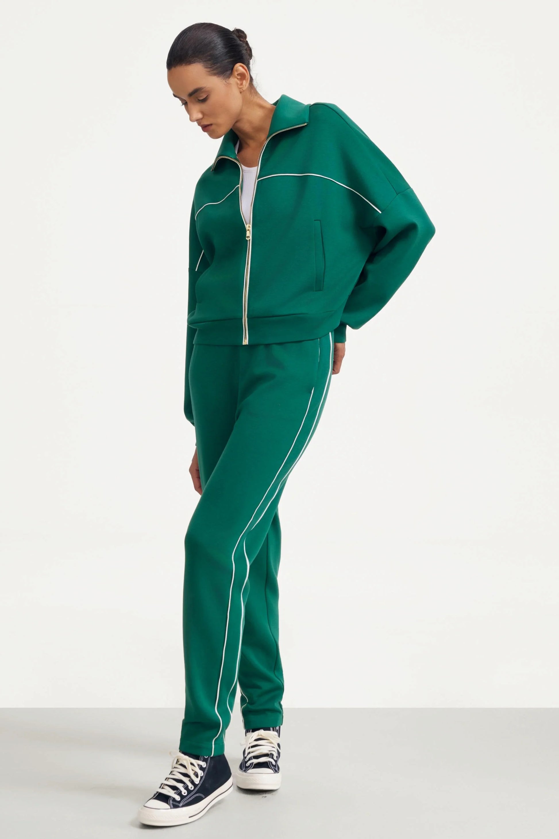 Angled view of women's deep teal slim fit golf pants with contrast piping