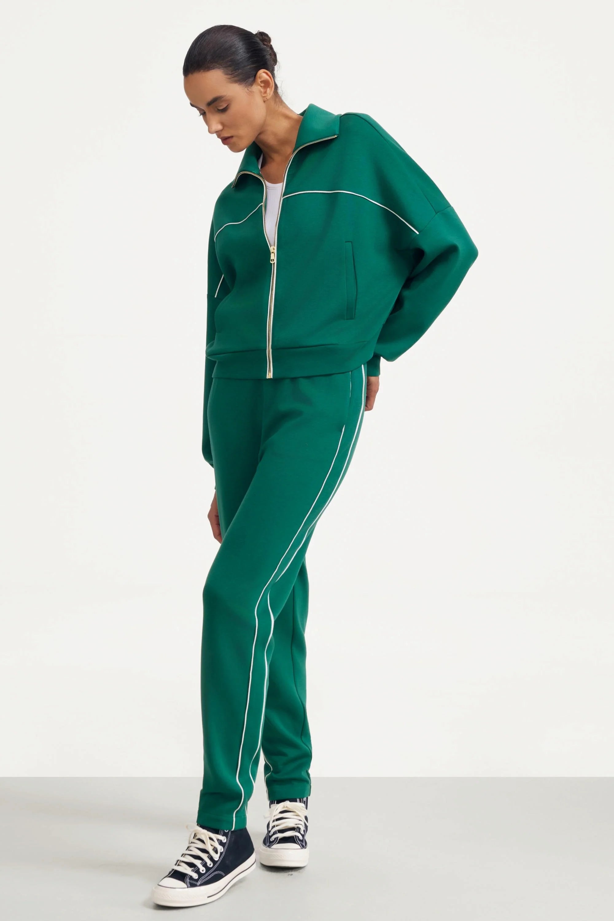 Angled view of women's deep teal slim fit golf pants with contrast piping
