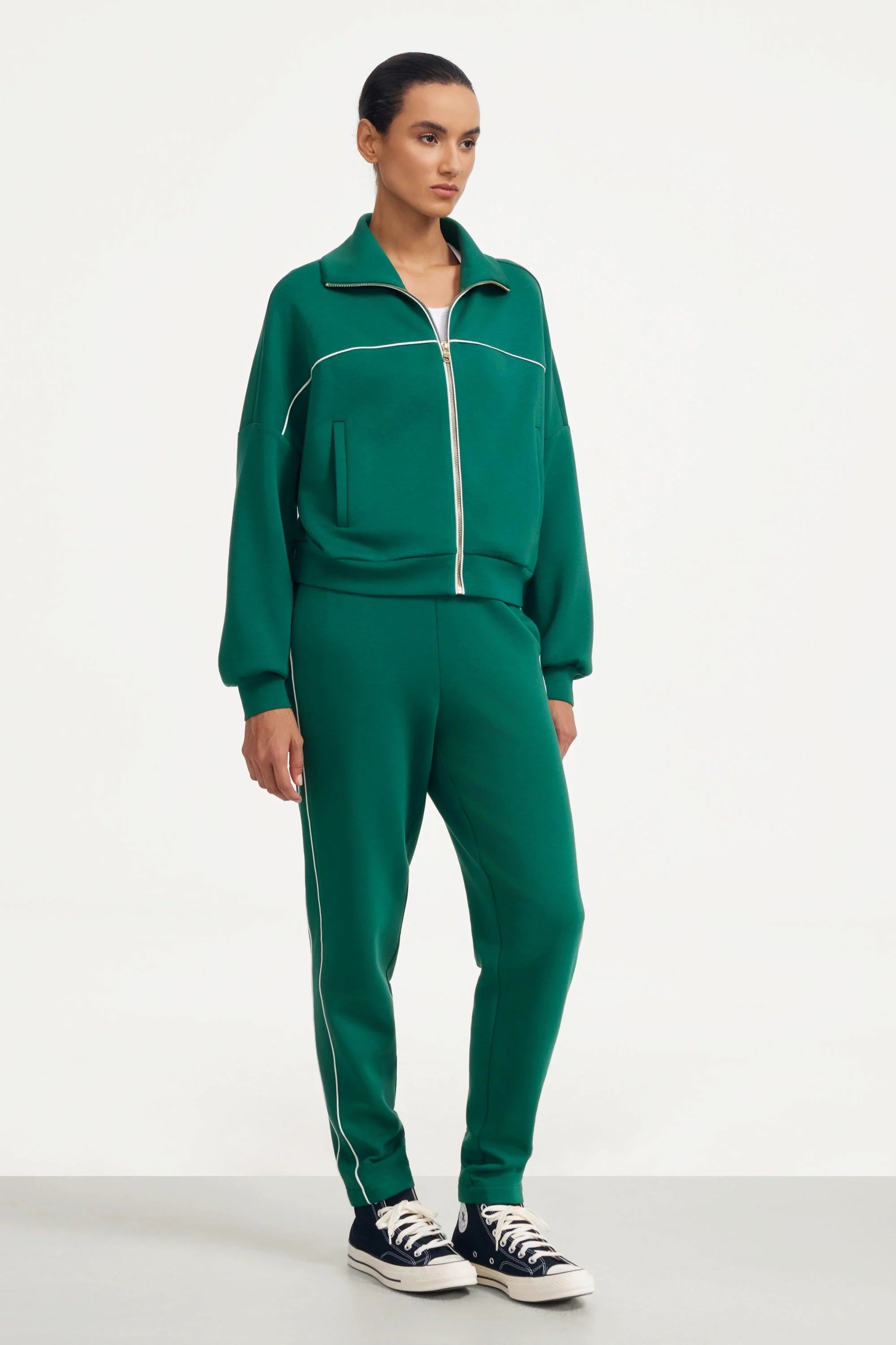 Front view of women's deep teal track pants styled with a matching zip jacket