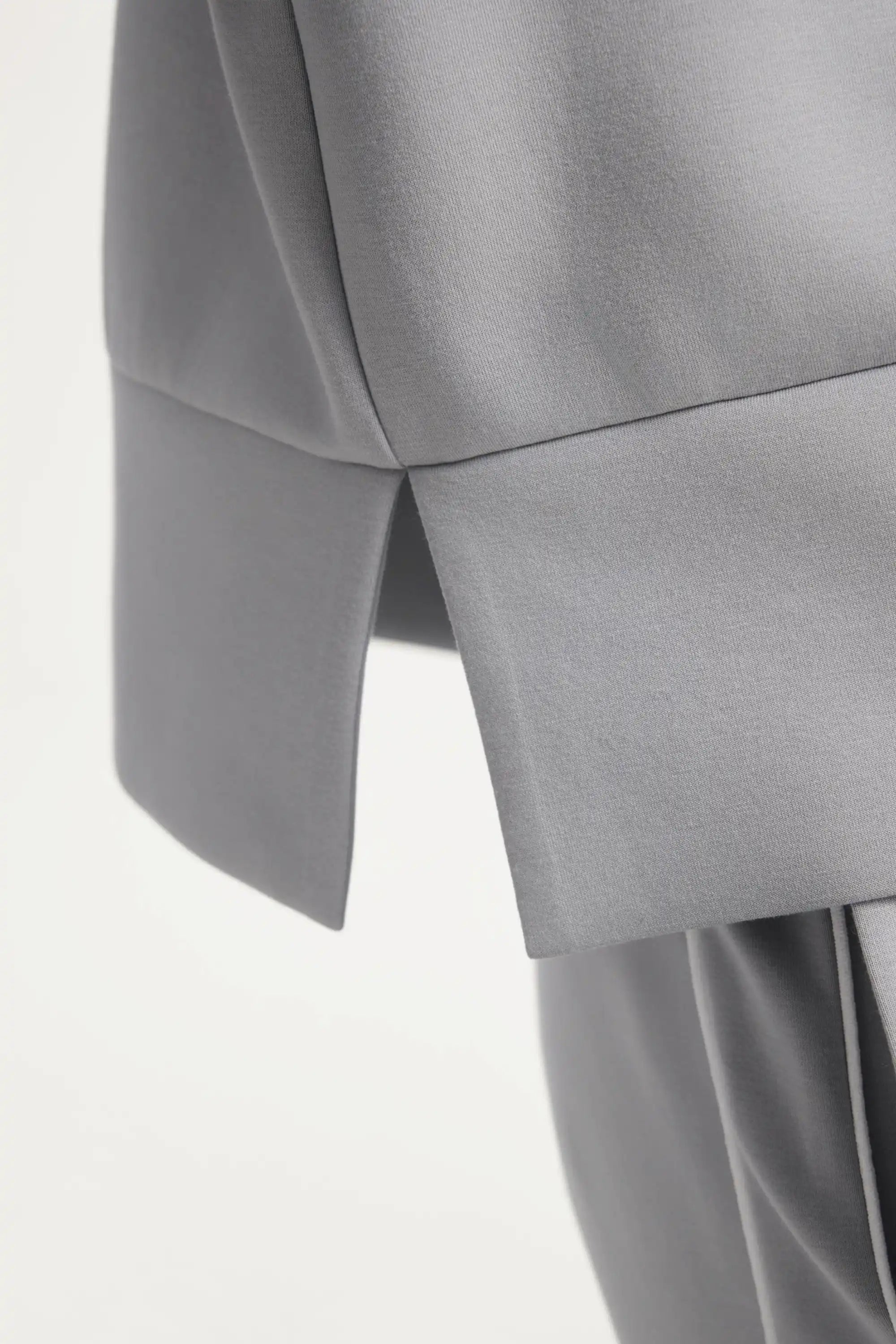Close-up of the side hem slit detail on a women’s half-zip golf pullover in Soft Cloud Grey