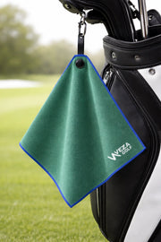Green magnetic golf towel hanging from a golf bag on the course