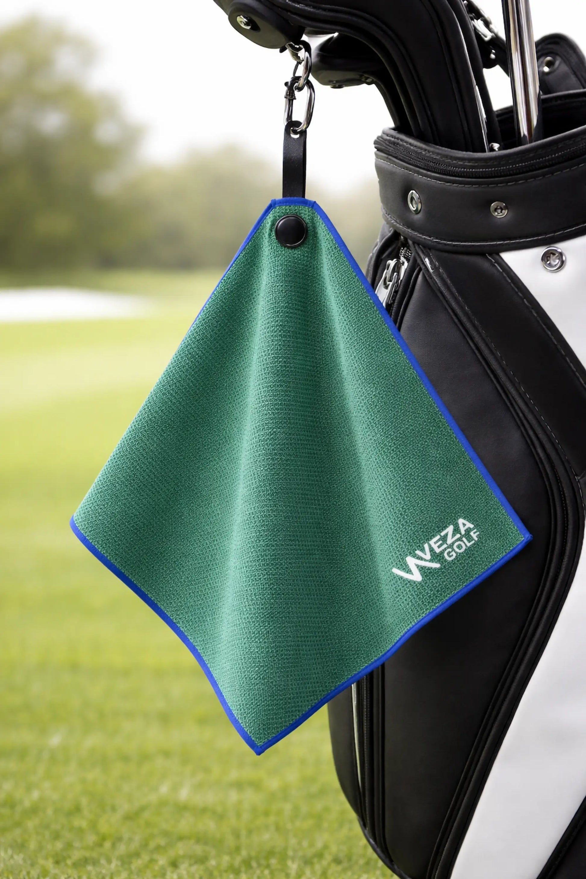 Green magnetic golf towel hanging from a golf bag on the course