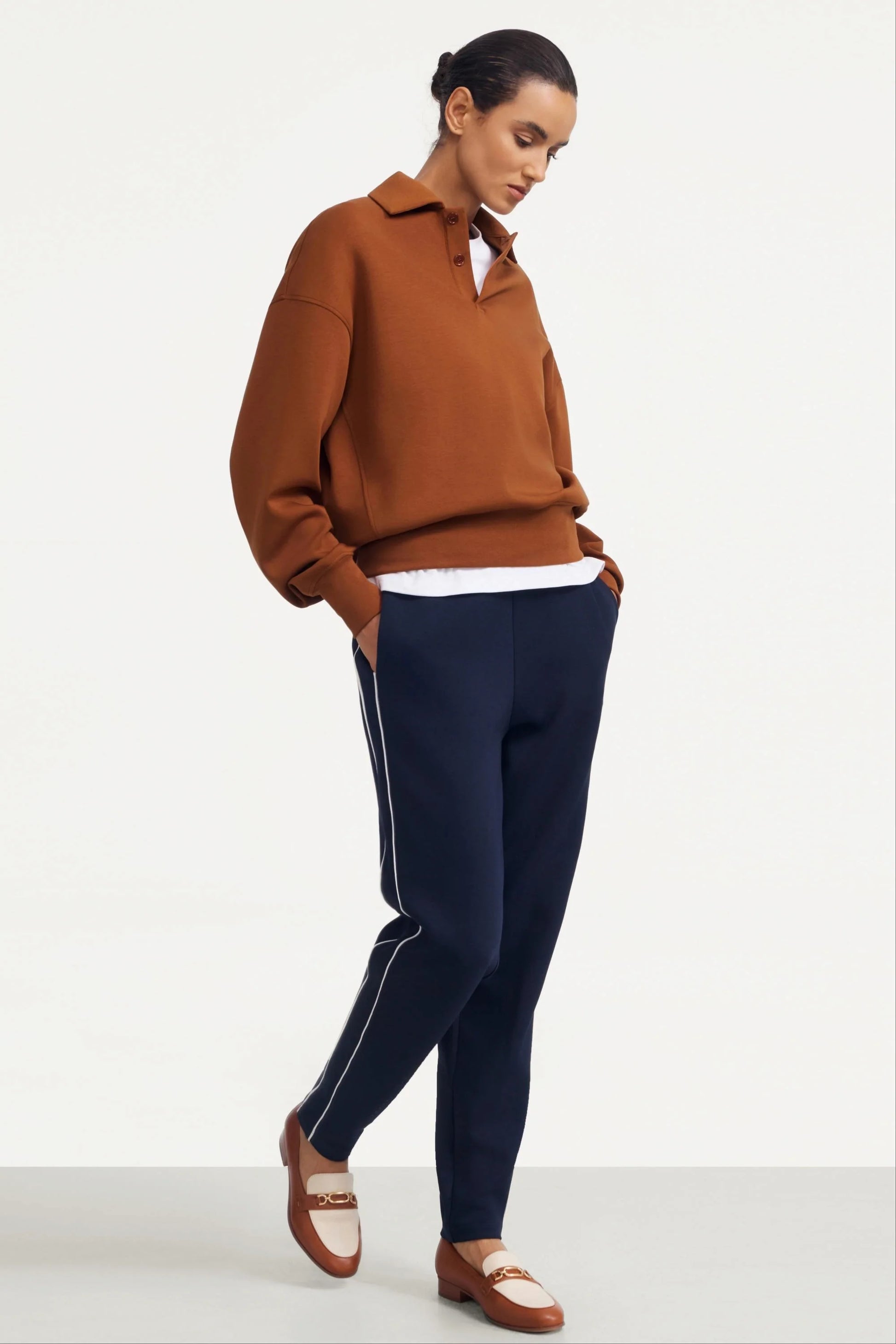 Woman wearing Midnight Navy slim fit golf pants styled with a brown pullover