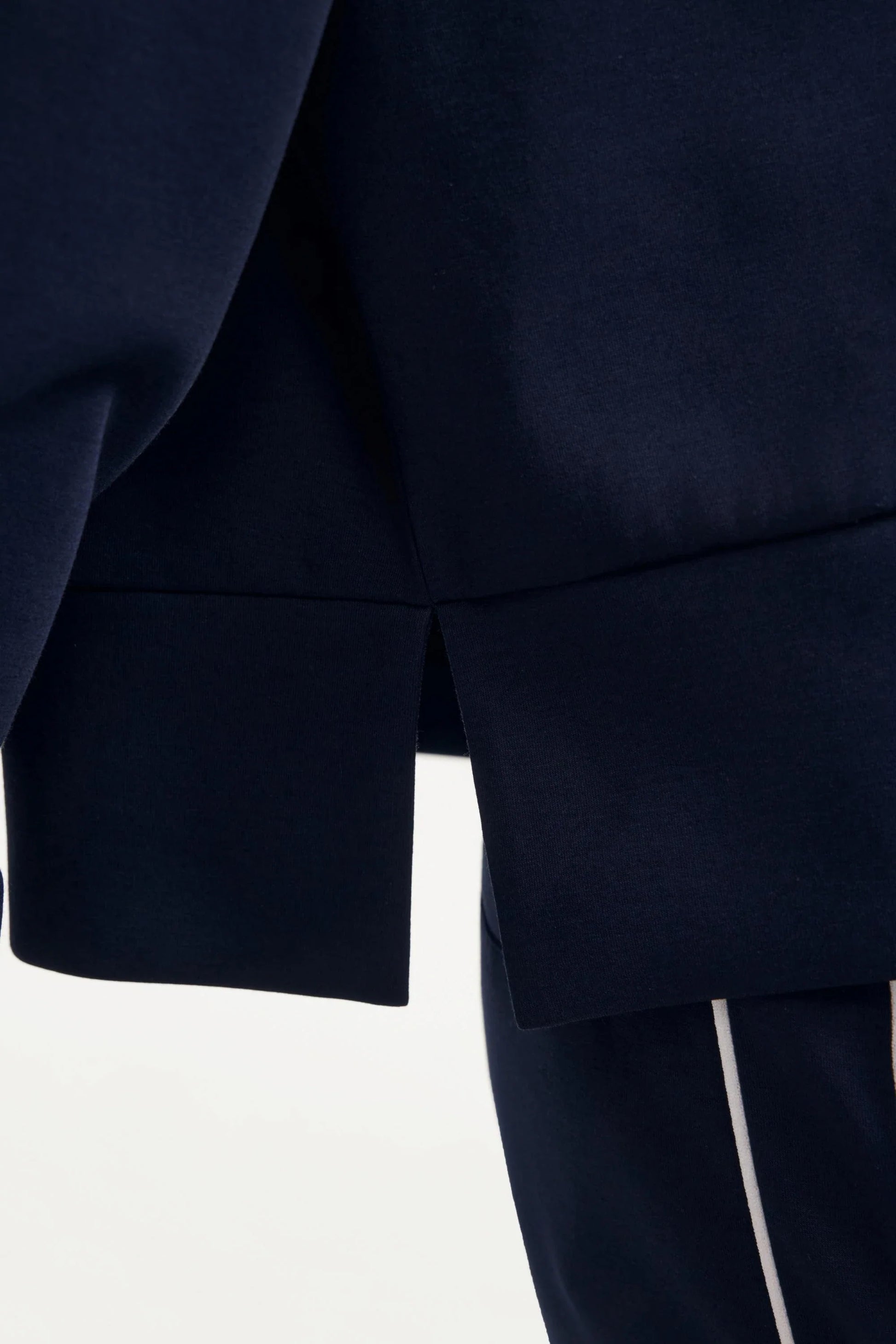 Close-up of the side hem slit on a women’s half-zip golf pullover in Midnight Navy showing the structured design