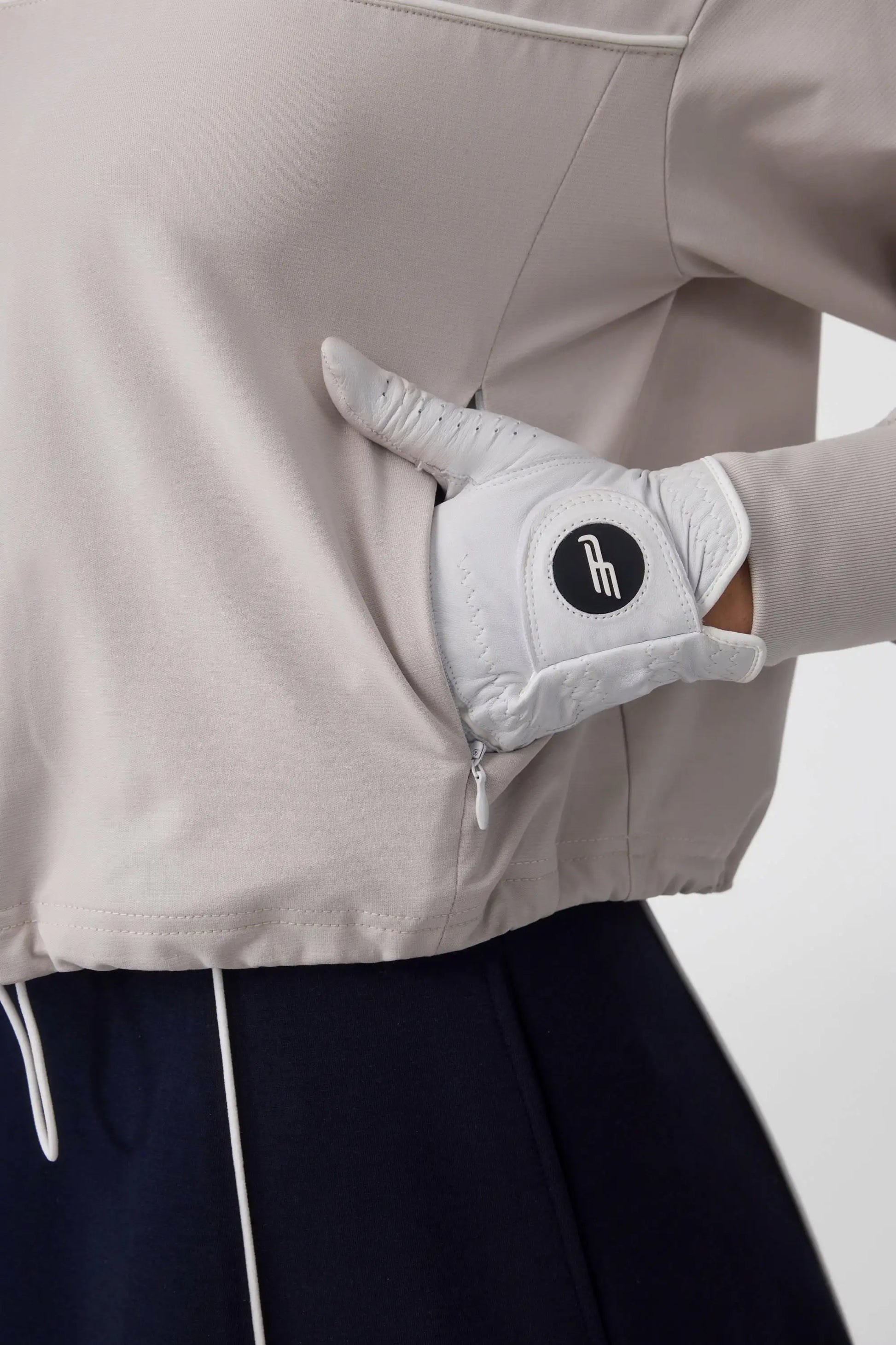 Close-up of the side zip pocket detail on a soft taupe golf top