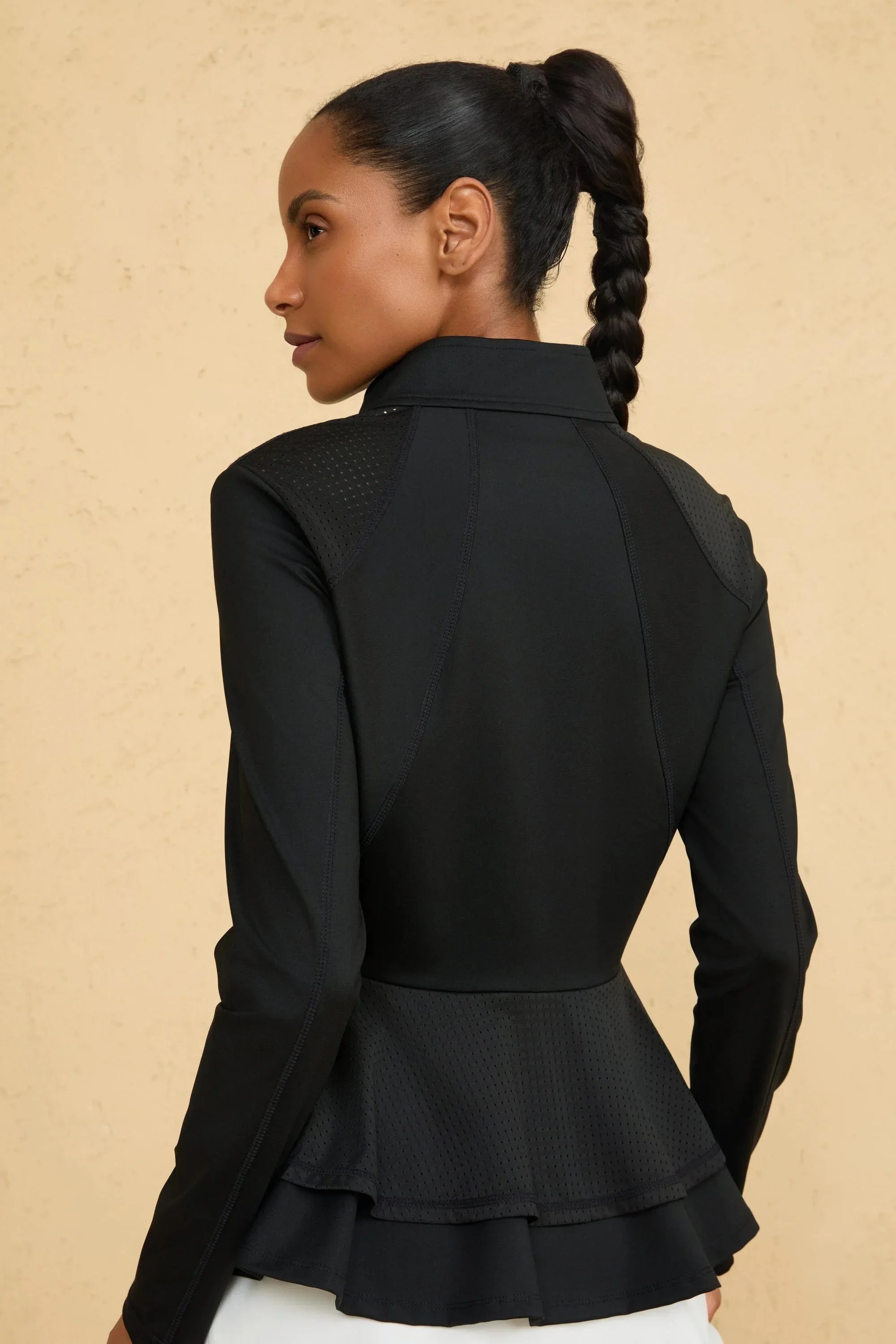 Back view of VEZA onyx black mesh-panel zip jacket with a defined peplum silhouette