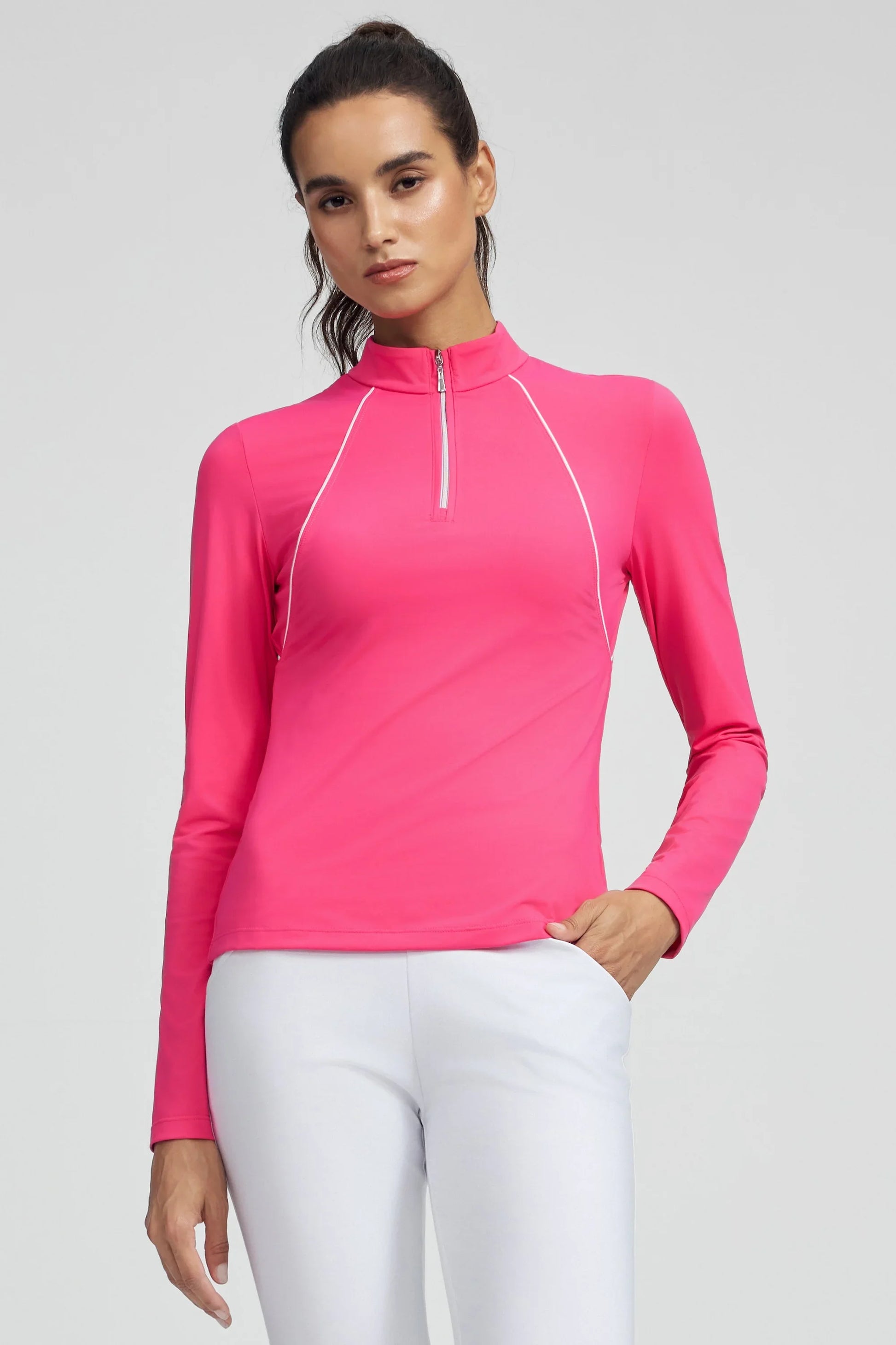 Woman wearing VEZA hot pink piped quarter-zip performance top with UPF 50+, styled with white athletic pants, front view