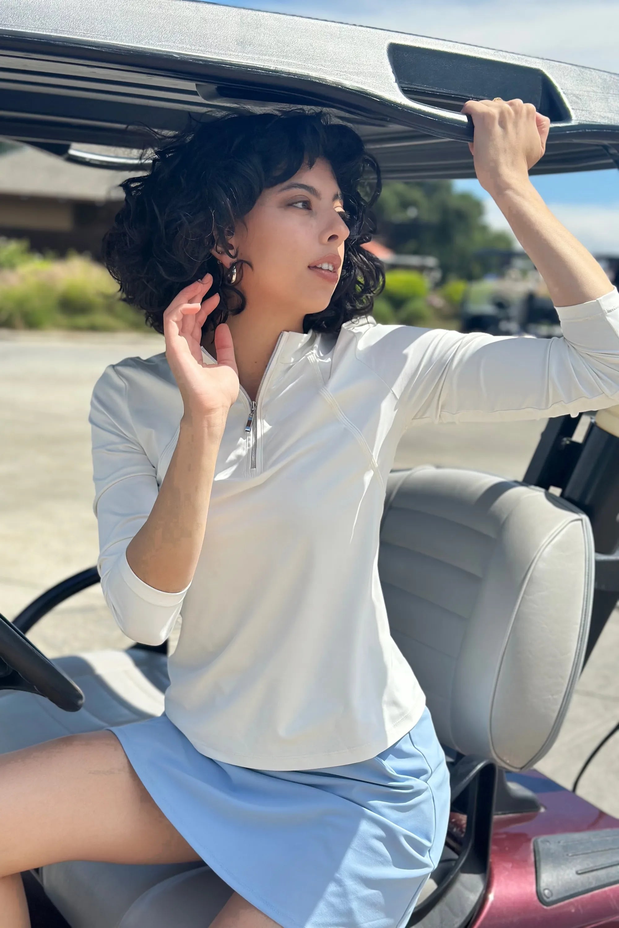 VEZA white quarter-zip performance top worn on a golf cart, breathable and moisture-wicking for on-course comfort