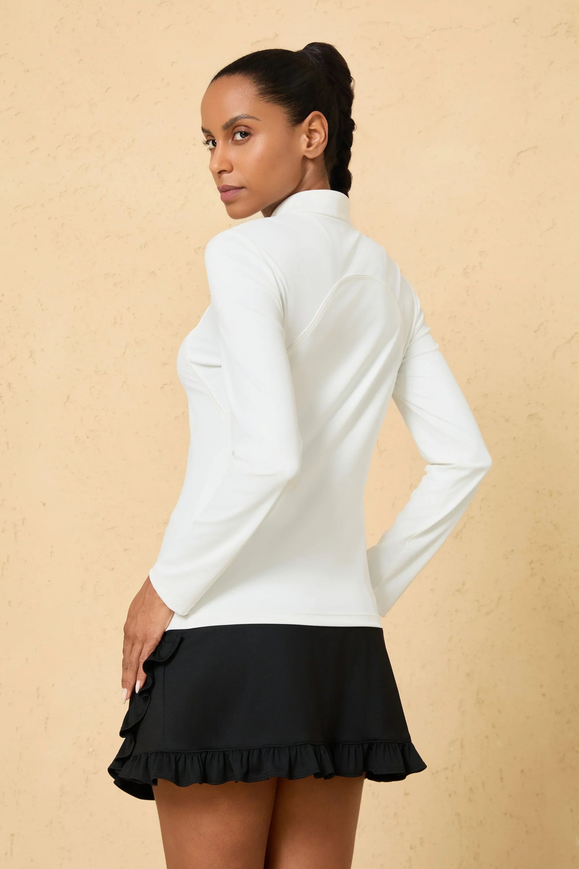 Side view of VEZA white quarter-zip performance top highlighting stretch fabric and streamlined design