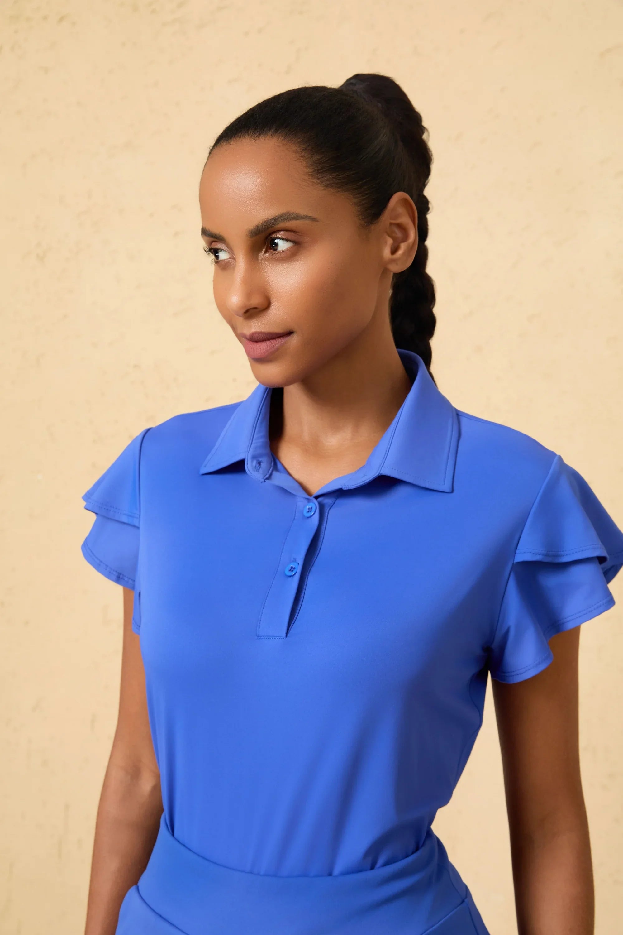 Close-up of VEZA cobalt bloom blue performance golf polo highlighting the ruffle sleeve and breathable collar detail