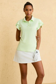 Woman wearing VEZA fairway mint ruffle-sleeve performance golf polo with UPF 50+, styled with a white golf skirt, front view