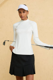 Woman wearing VEZA cloud white seamline mock-neck performance top with UPF 50+, styled with a black golf skirt, front view