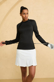 Women wearing VEZA black seamline mock-neck performance top with UPF 50+, styled with a white golf skirt, front view