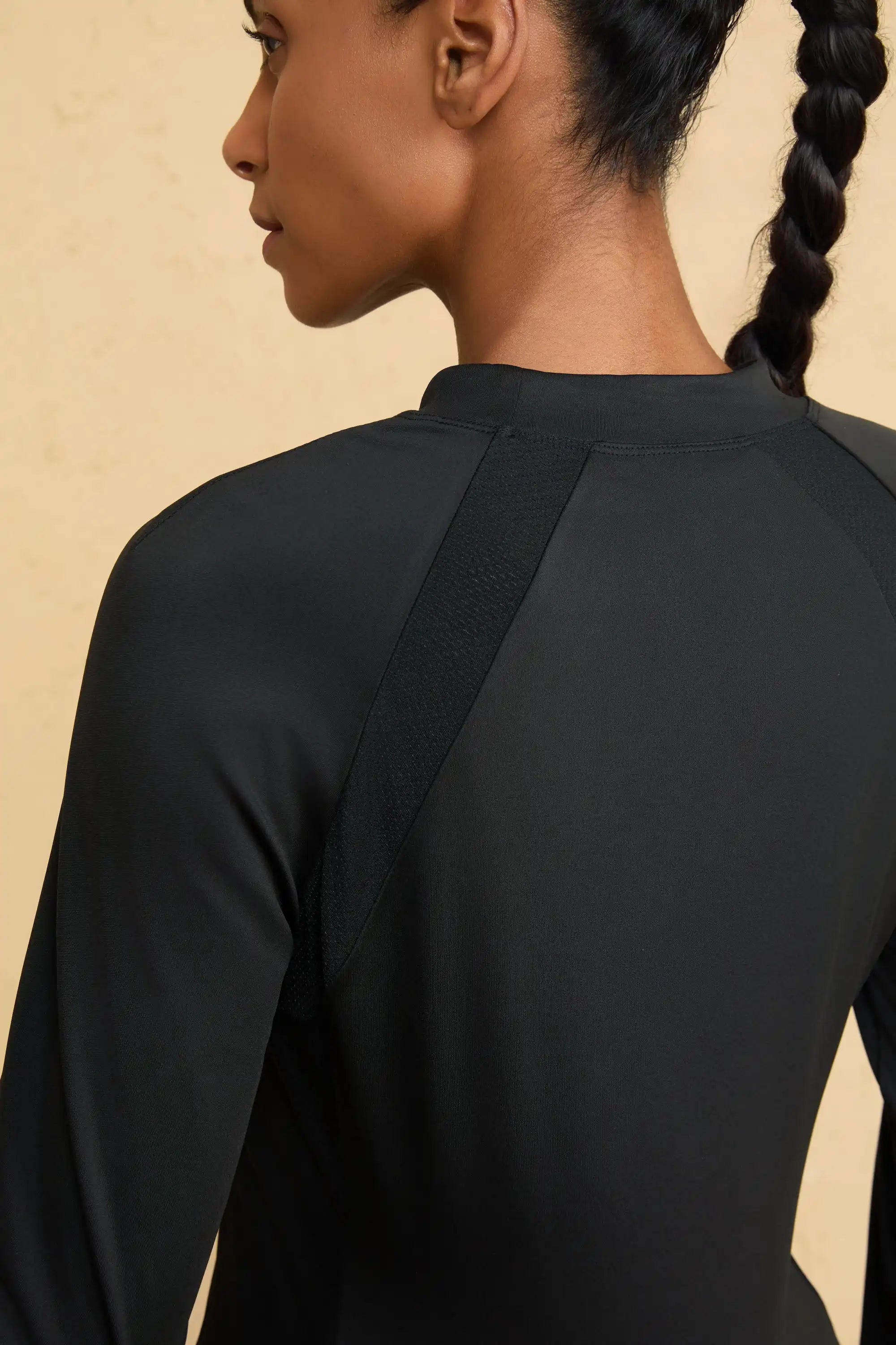 Close-up of VEZA black mock-neck performance top showing breathable, seamless shoulder fabric detail