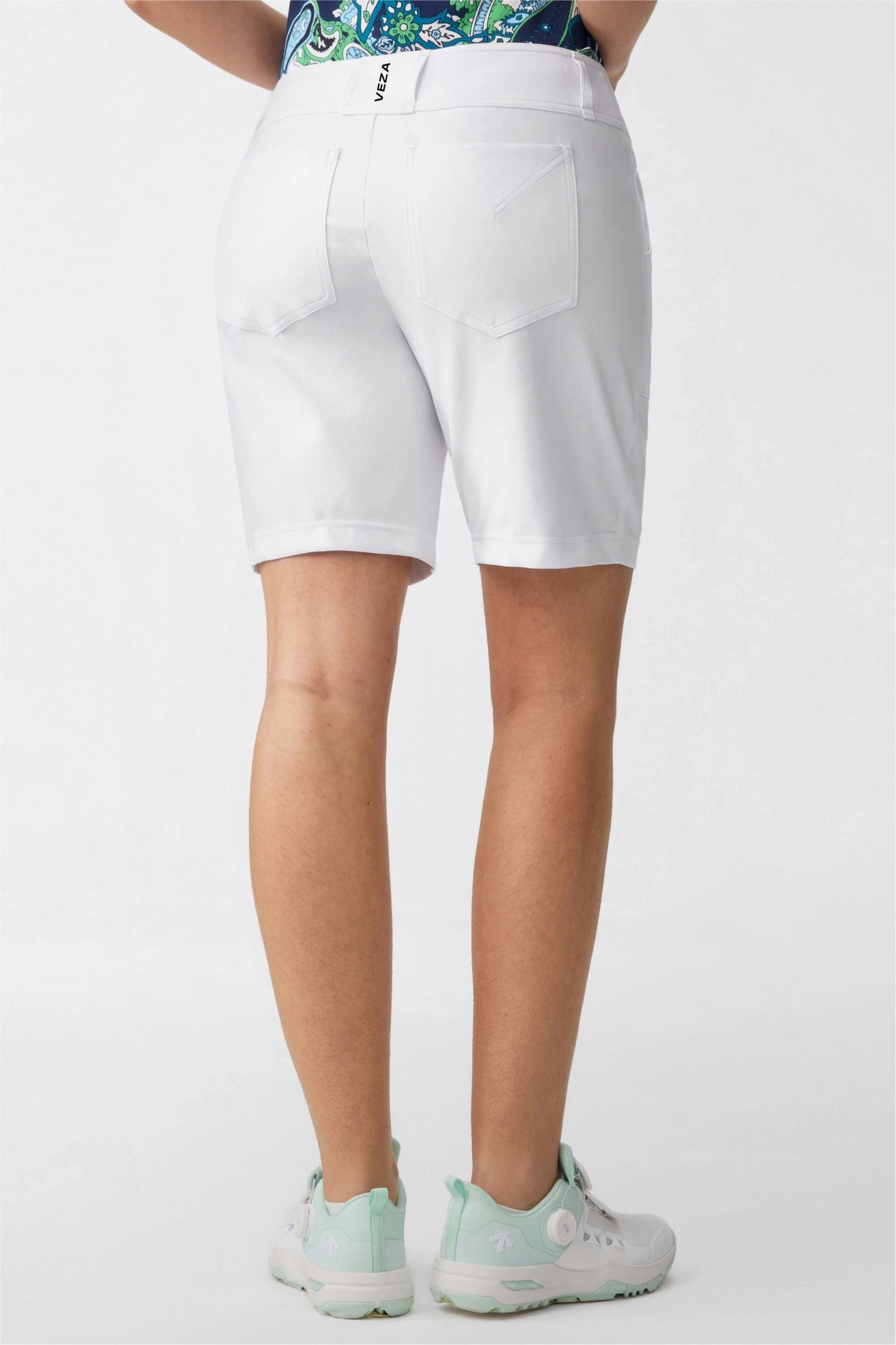 Back angled view of women’s white bermuda golf shorts showing tailored fit and back pocket details
