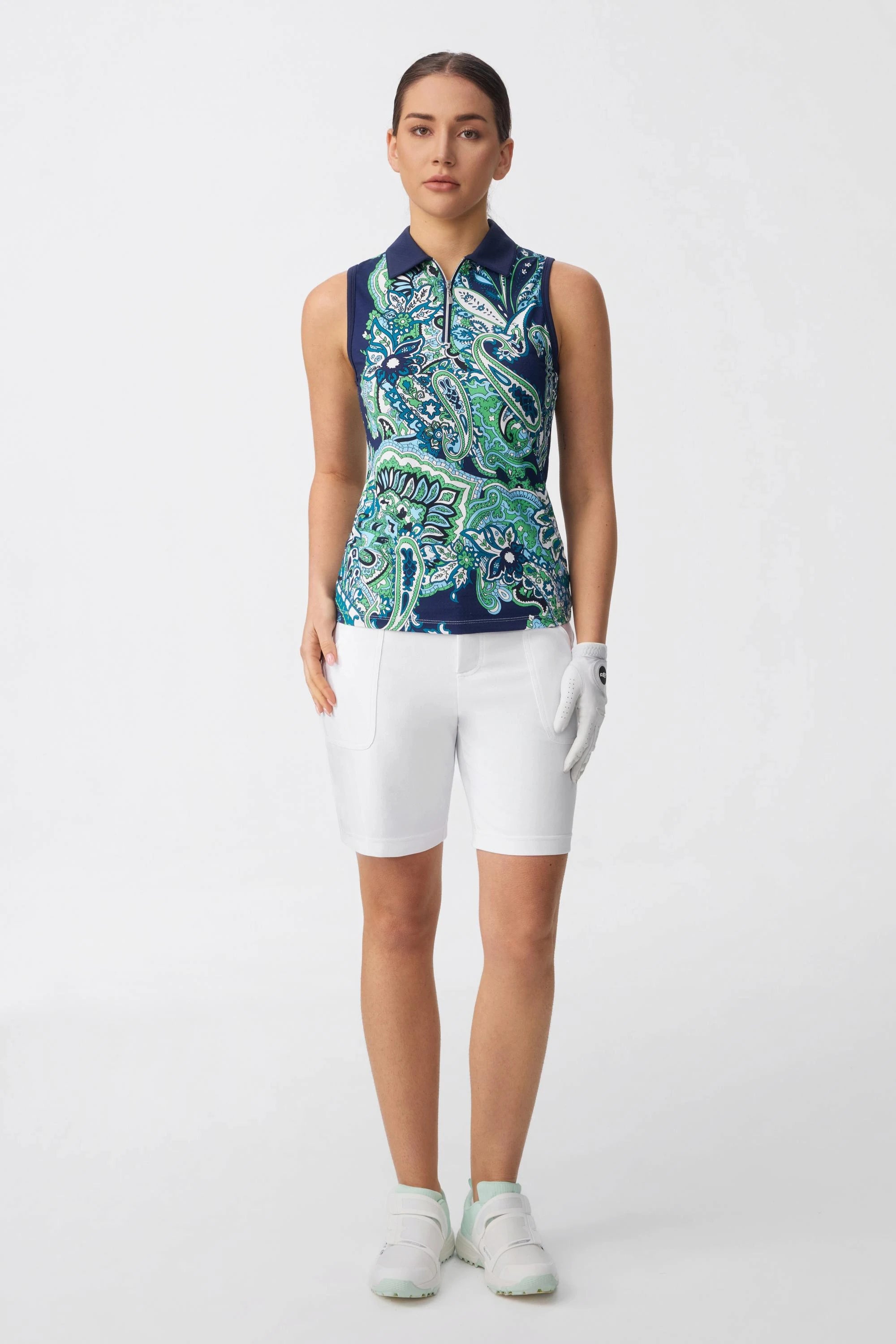 Model wearing women’s white bermuda golf shorts with a sleeveless printed golf top