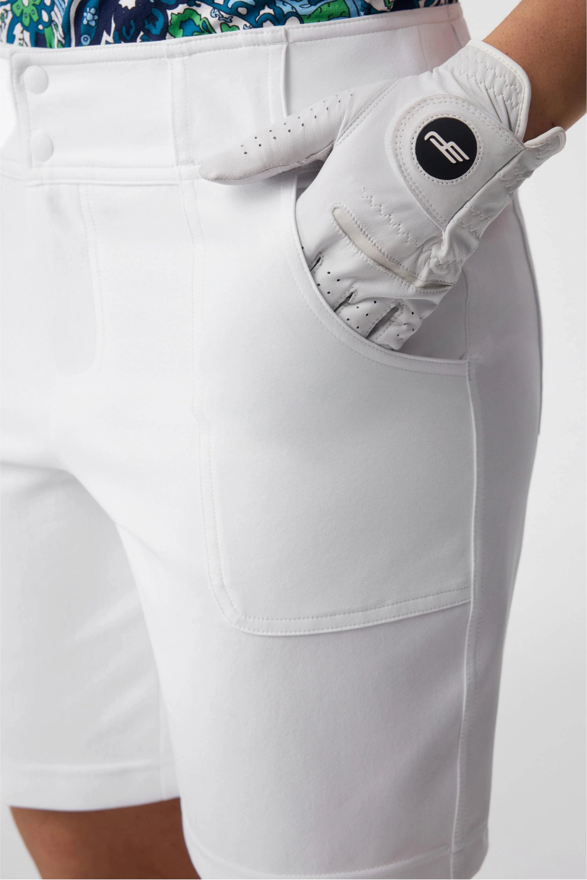Close-up of women’s white bermuda golf shorts showing utility pocket detail and smooth stretch fabric