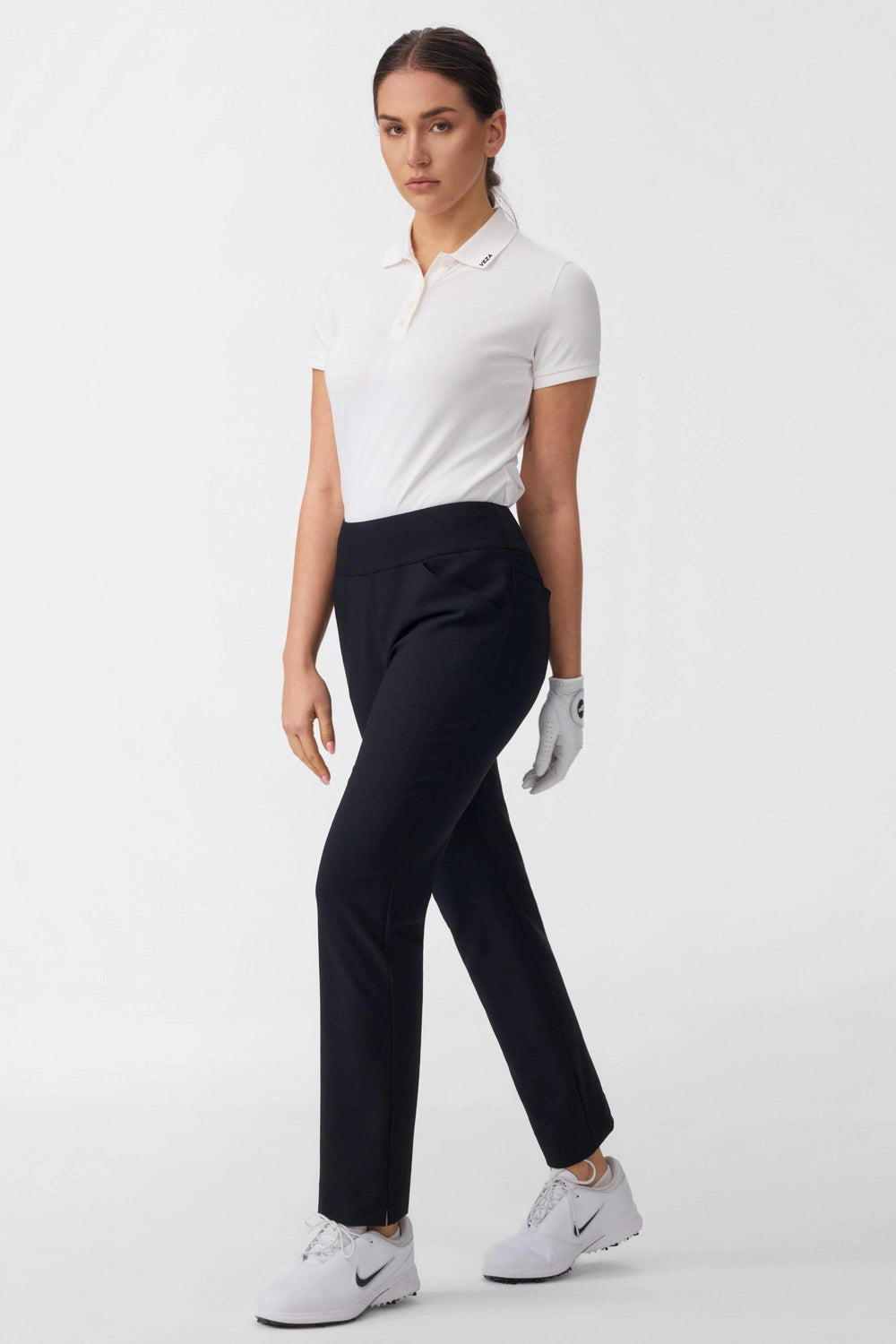 Model walking in women’s onyx black tapered golf pants on a golf course inspired outfit