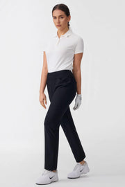 Model walking in women’s onyx black tapered golf pants on a golf course inspired outfit