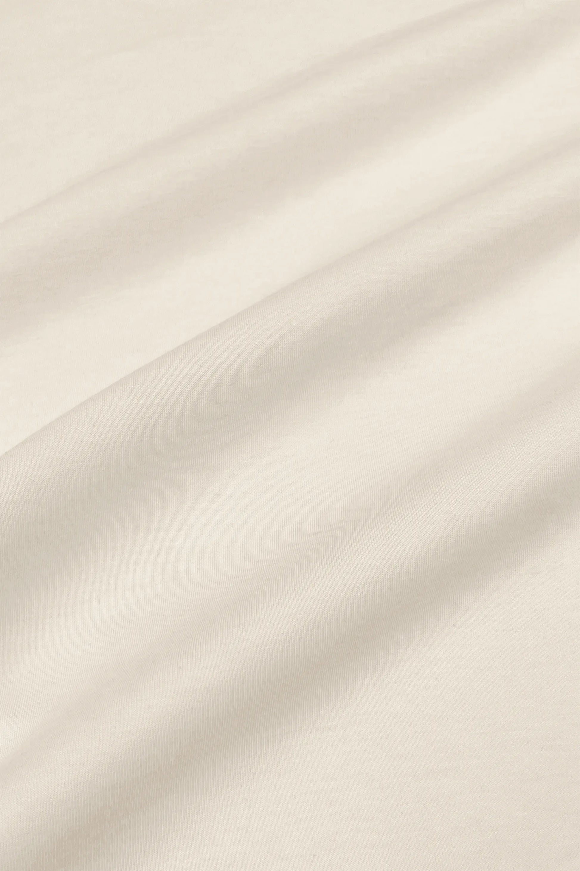 Close-up of the smooth ivory fabric texture on the women’s barrel leg pants