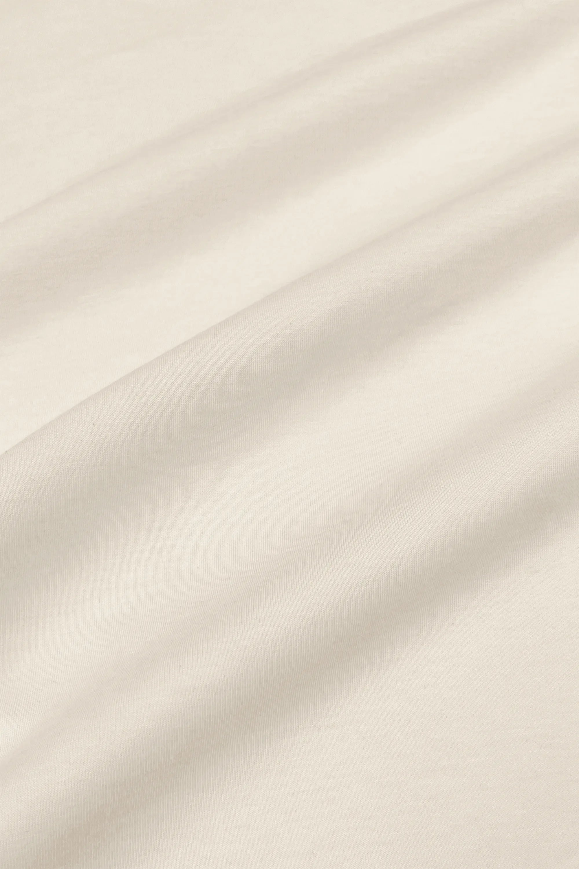 Close-up of the smooth ivory fabric texture on the women’s barrel leg pants
