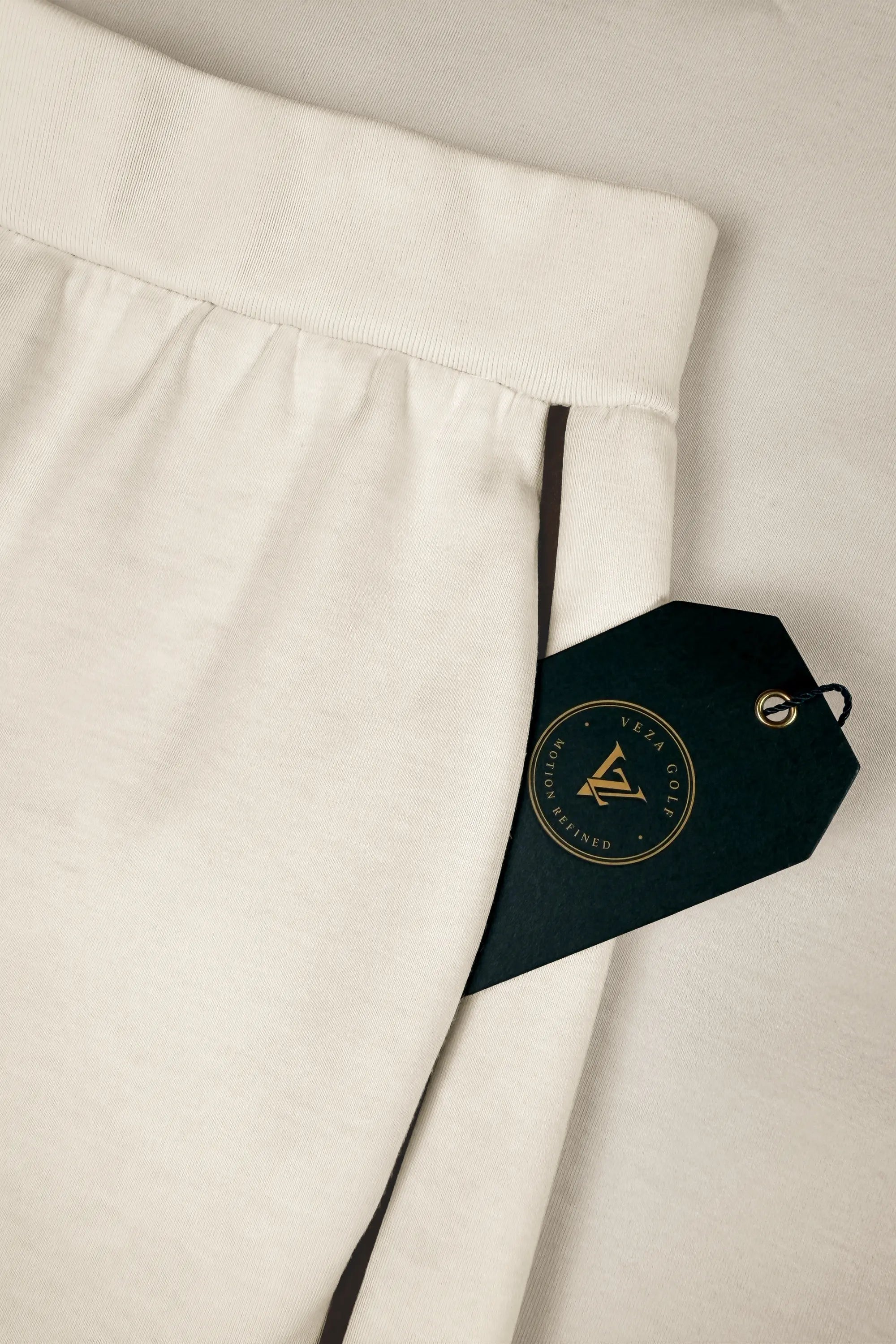 Close-up of women’s ivory barrel leg pants showing the waistband and dark contrast piping along the side