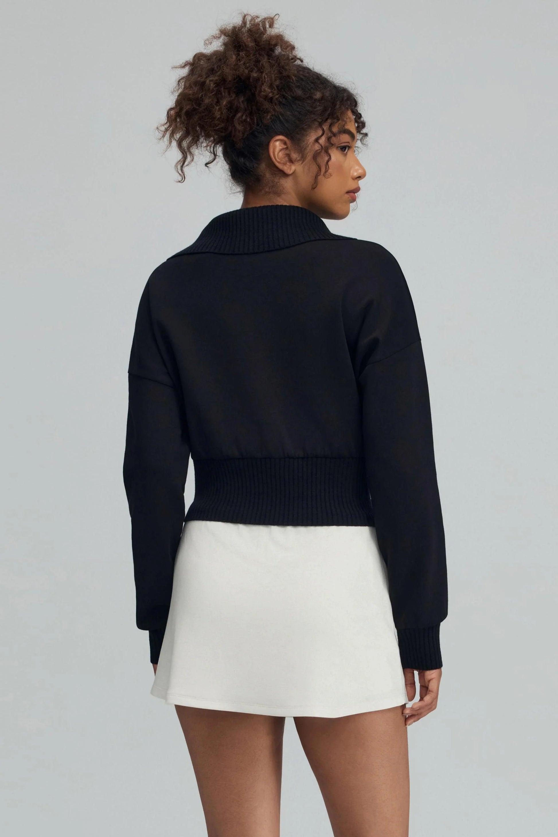 Back view of women’s black cropped knit zip jacket with cropped silhouette