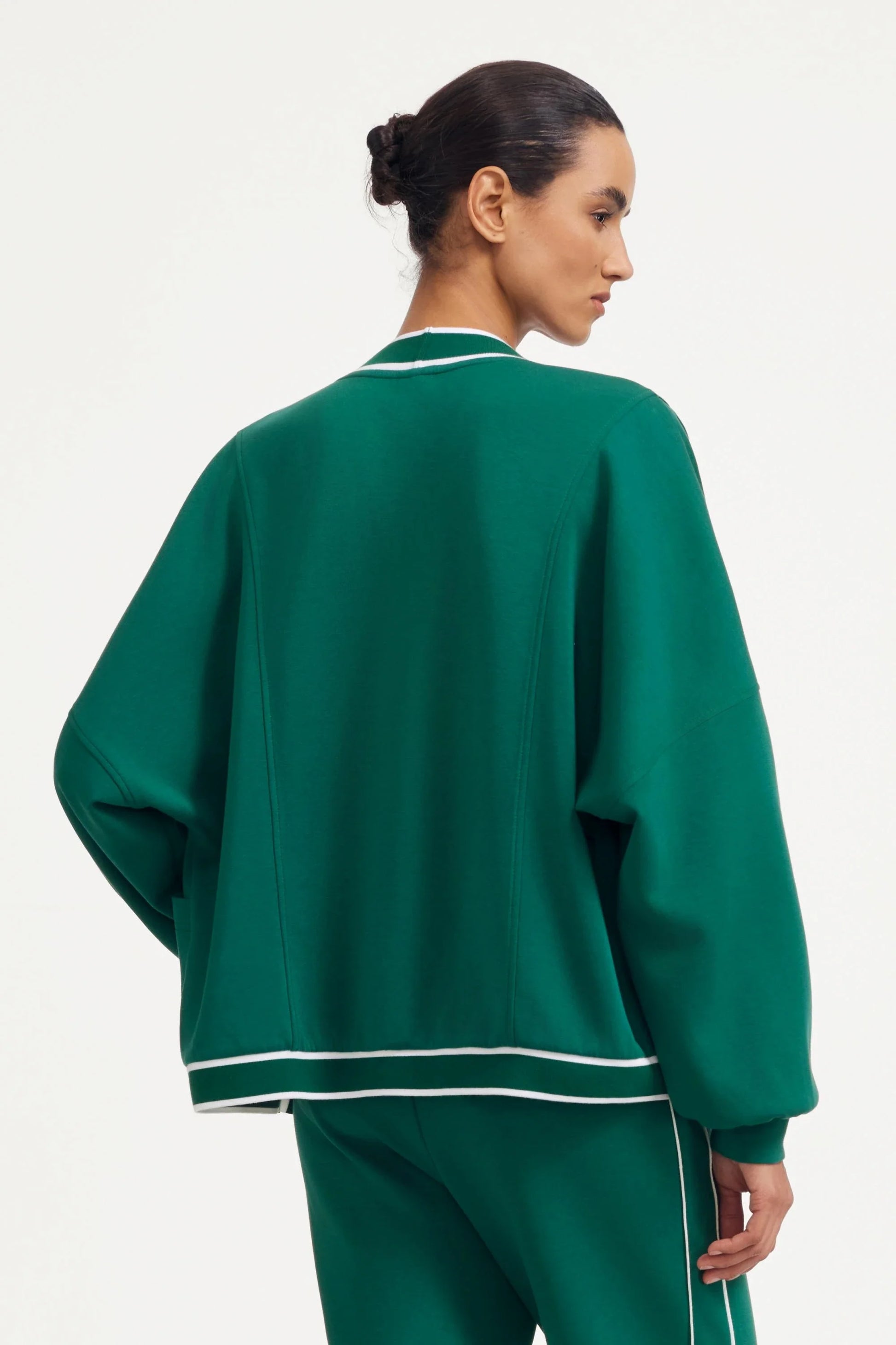Back view of a green women’s button cardigan with contrast trim