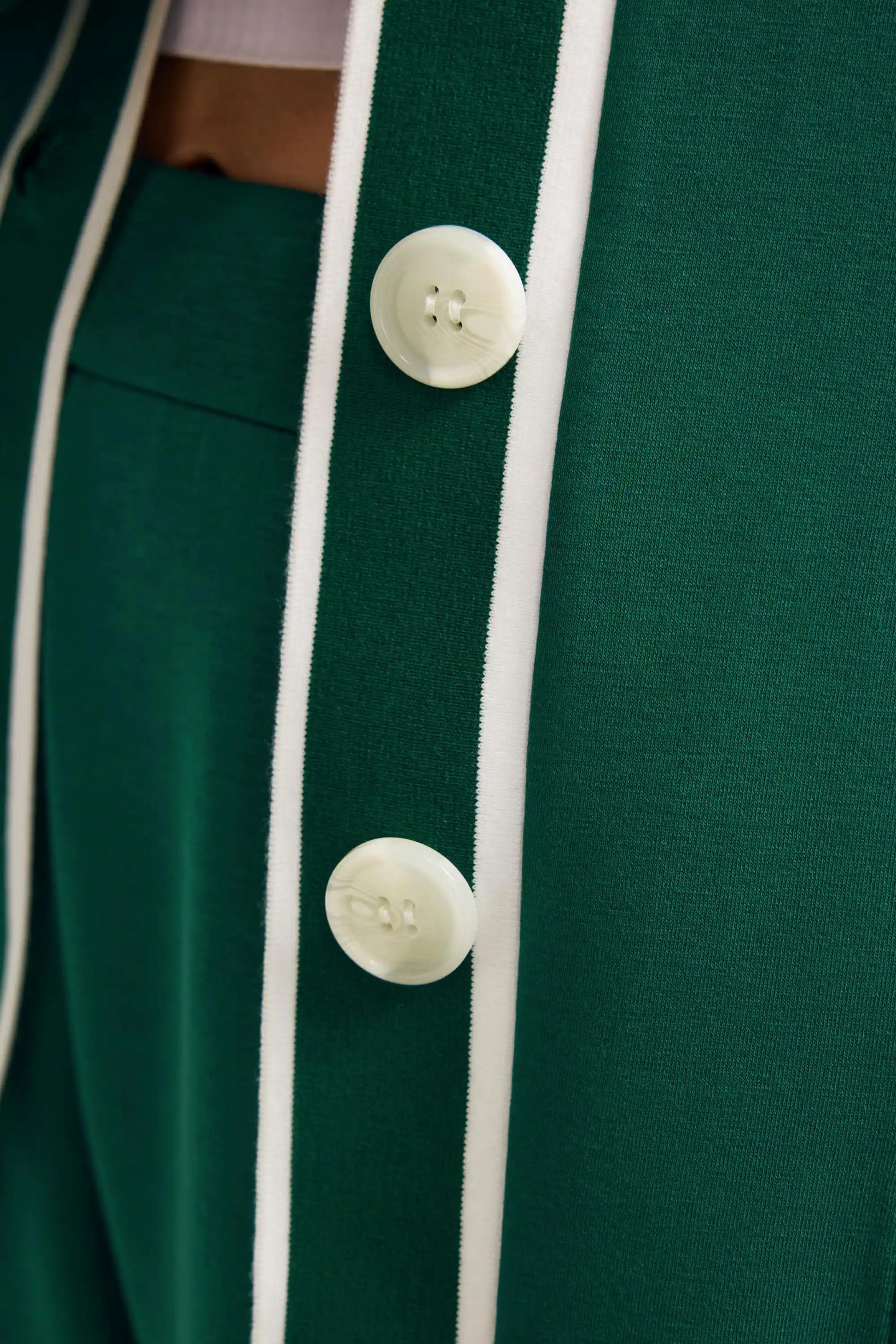Detail of the button placket and contrast trim on a deep teal women’s button cardigan