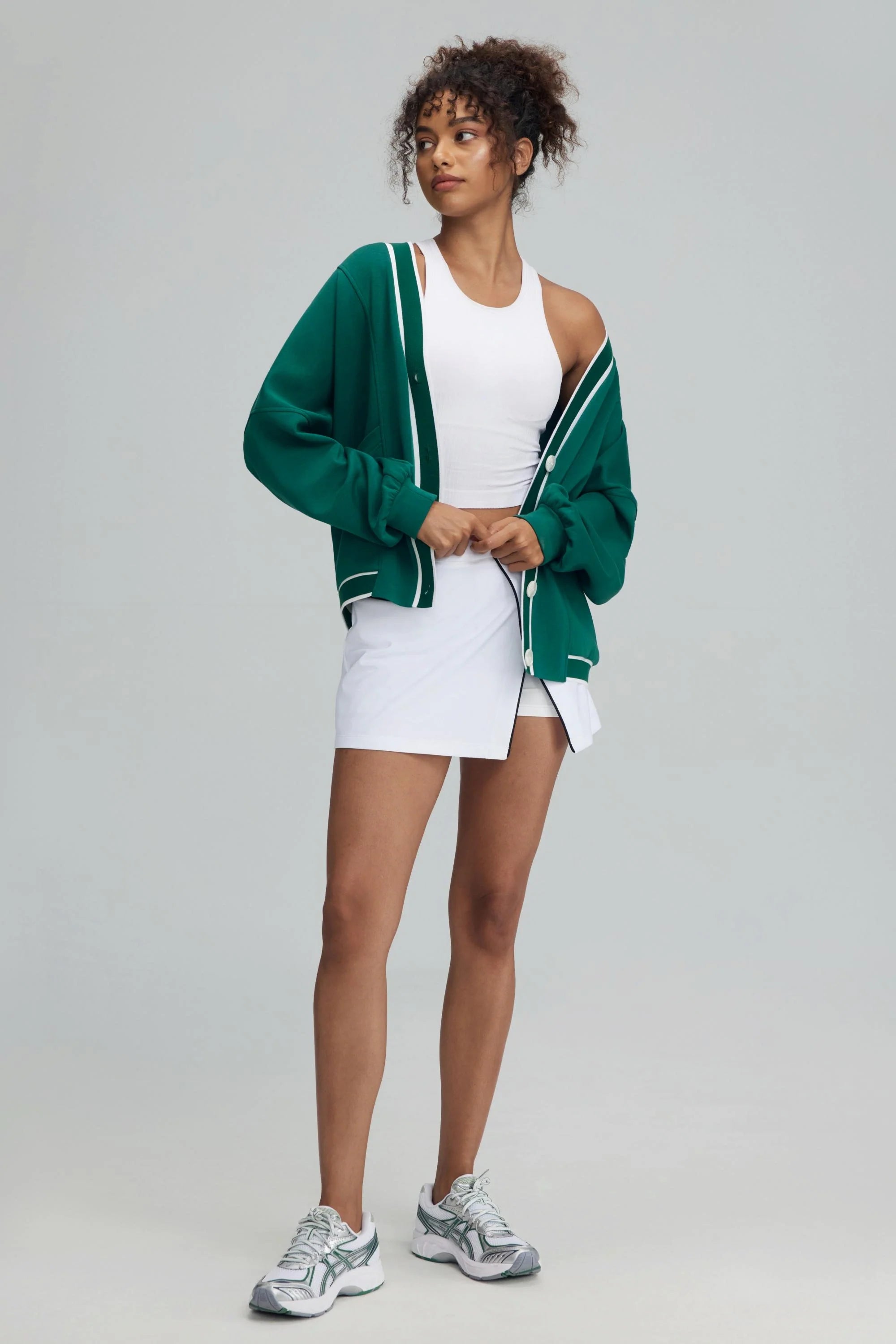 Deep teal women’s button cardigan worn open with a white skirt and white tank