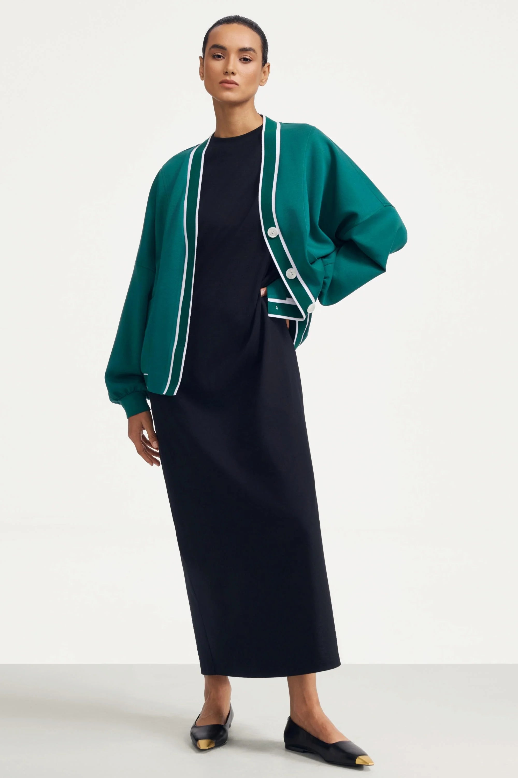 Woman wearing a green button cardigan layered over a black dress