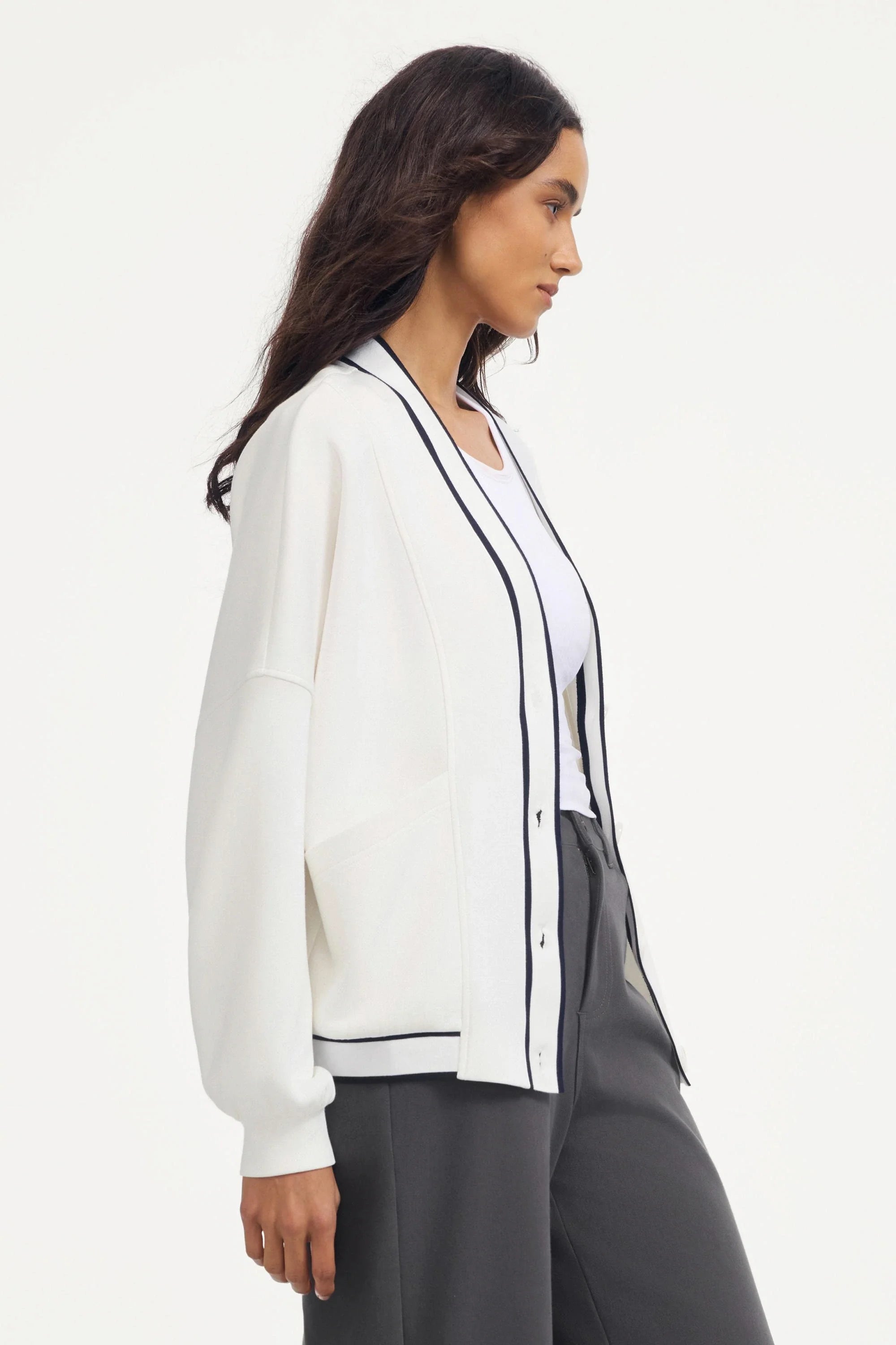 Side profile of a soft ivory women’s button cardigan with contrast trim and relaxed sleeves