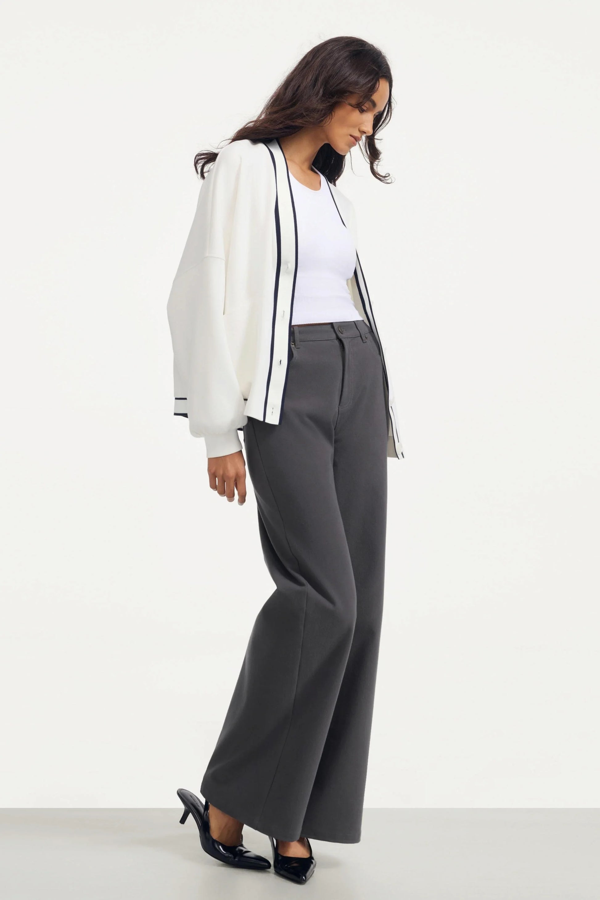 Side view of a women’s button cardigan in soft ivory styled with wide-leg pants