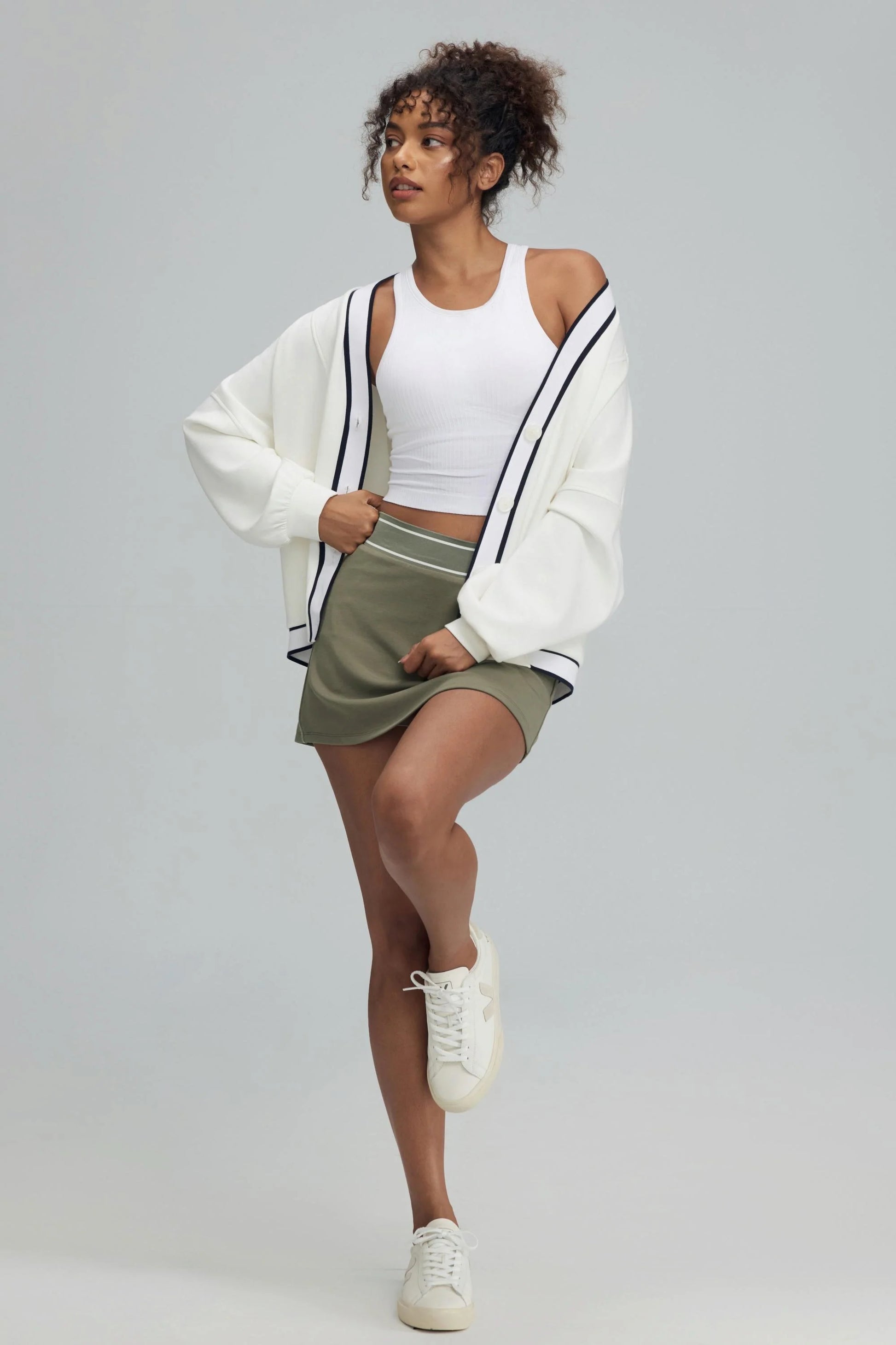 Soft ivory women’s button cardigan styled with a white tank and olive green skirt