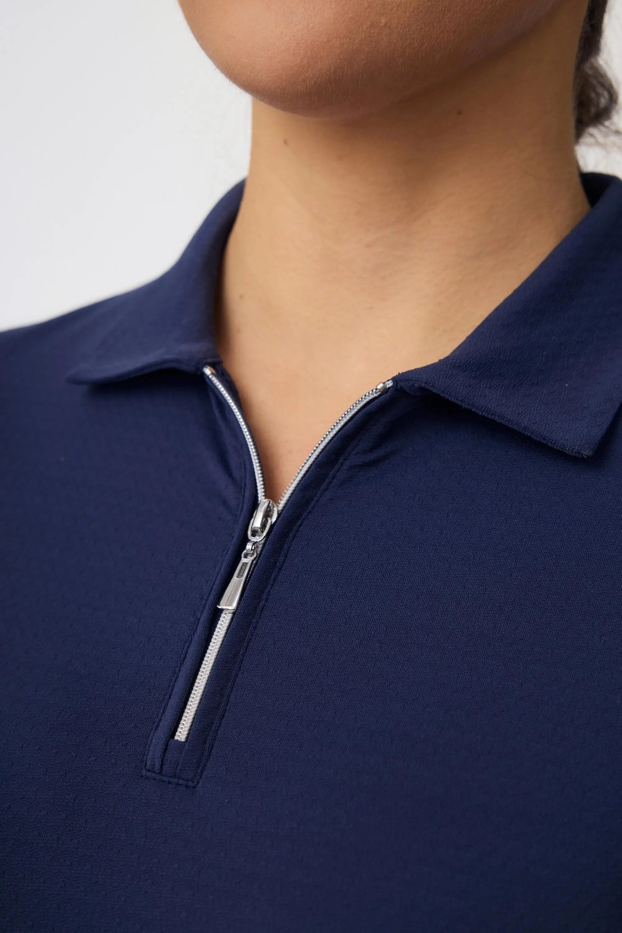 Close-up of the zip polo collar on a women’s navy contour golf dress with a refined sporty neckline