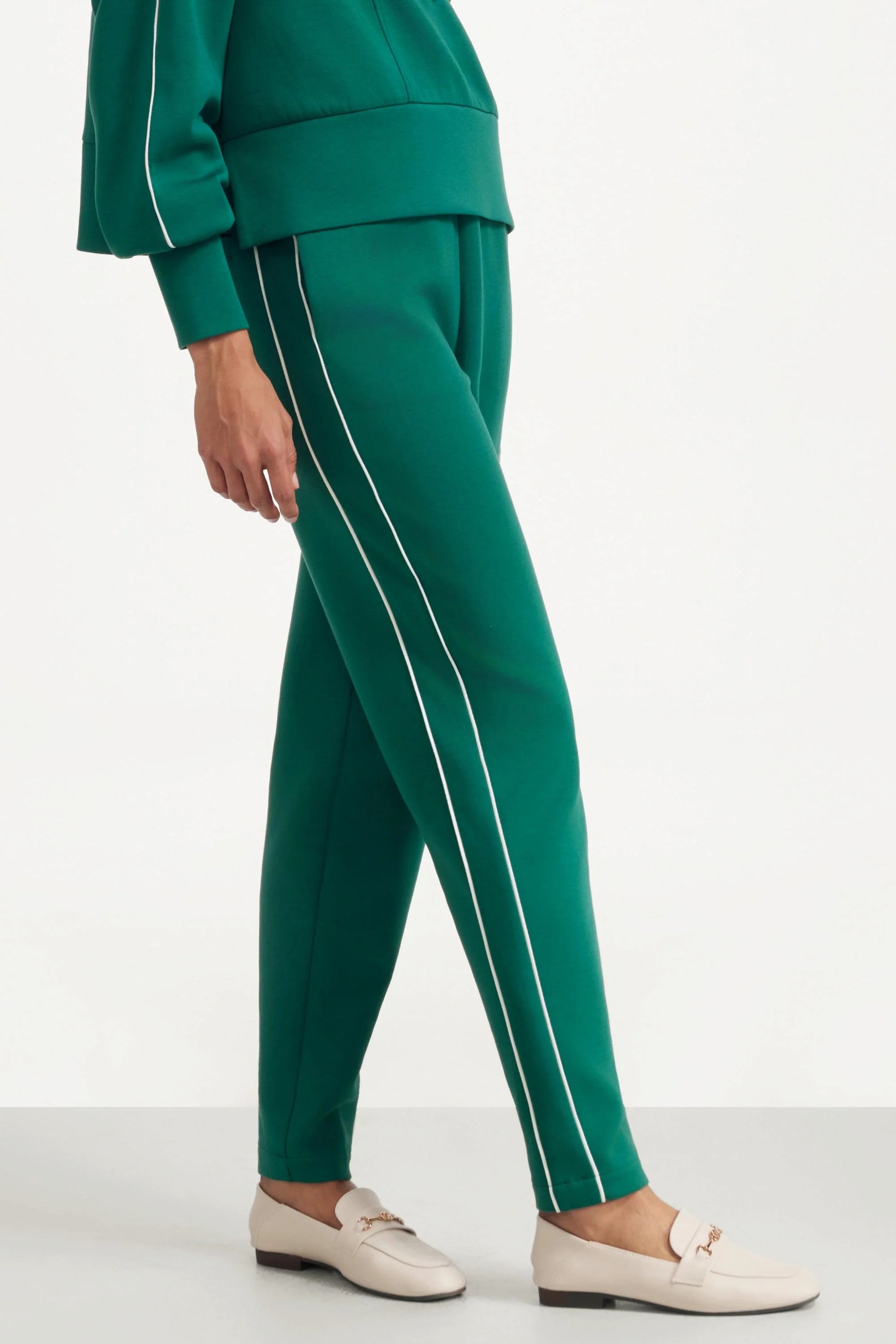 Side view of women's deep teal slim fit golf pants with contrast piping