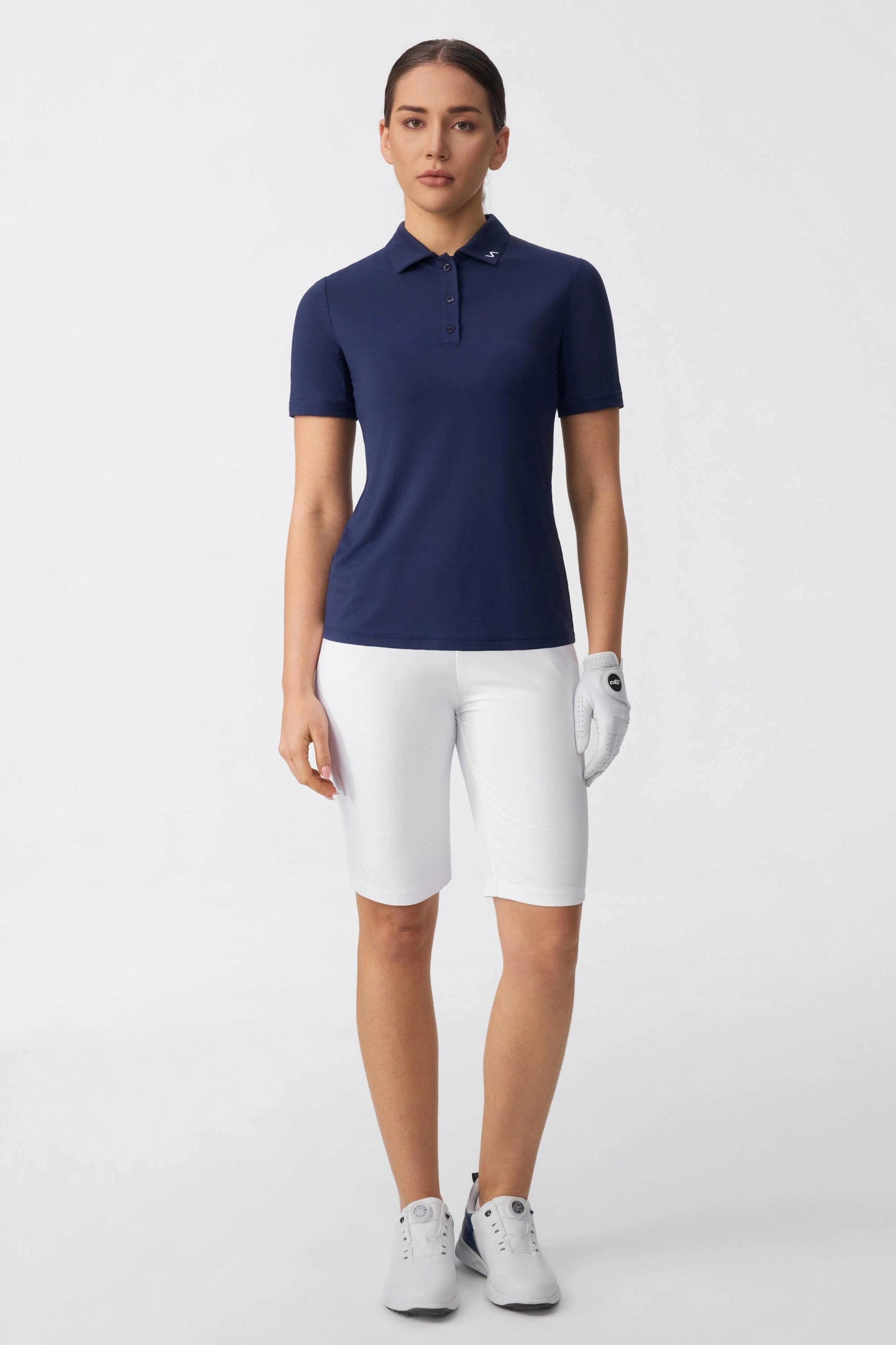 Women wearing cloudline tailored golf shorts styled with a navy performance golf polo