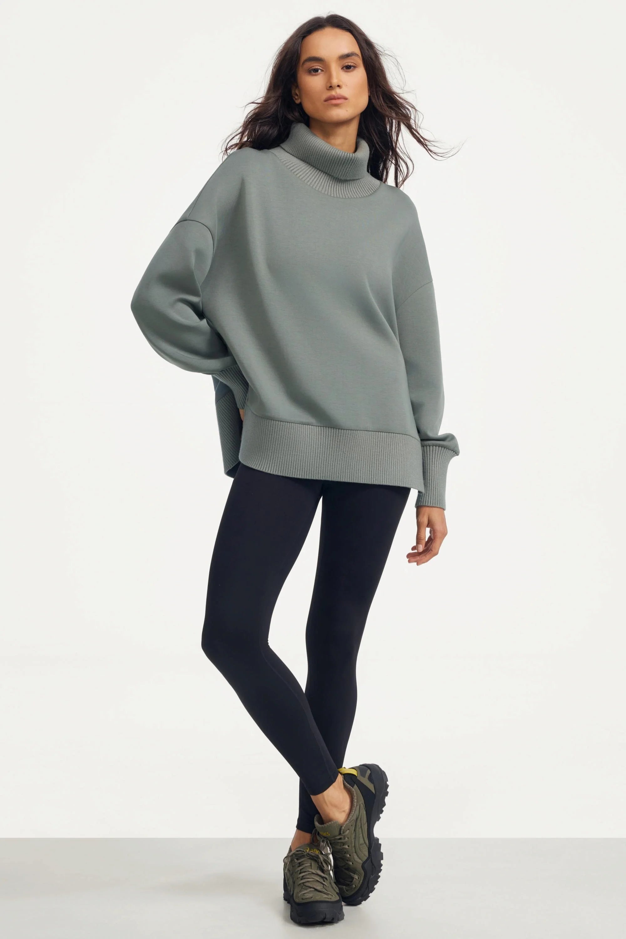 Women’s sage grey funnel-neck pullover paired with leggings and sneakers