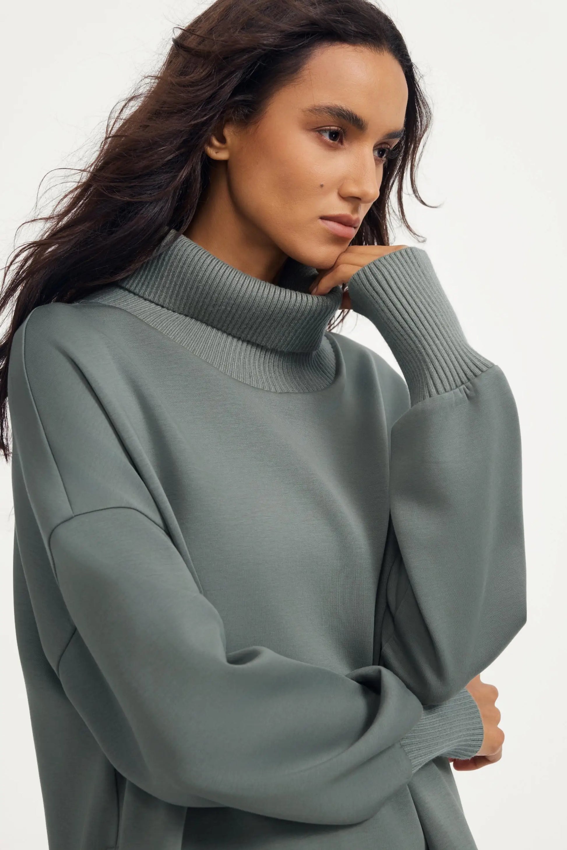 Portrait close-up of women’s sage grey funnel-neck pullover with relaxed drape and ribbed collar detailing
