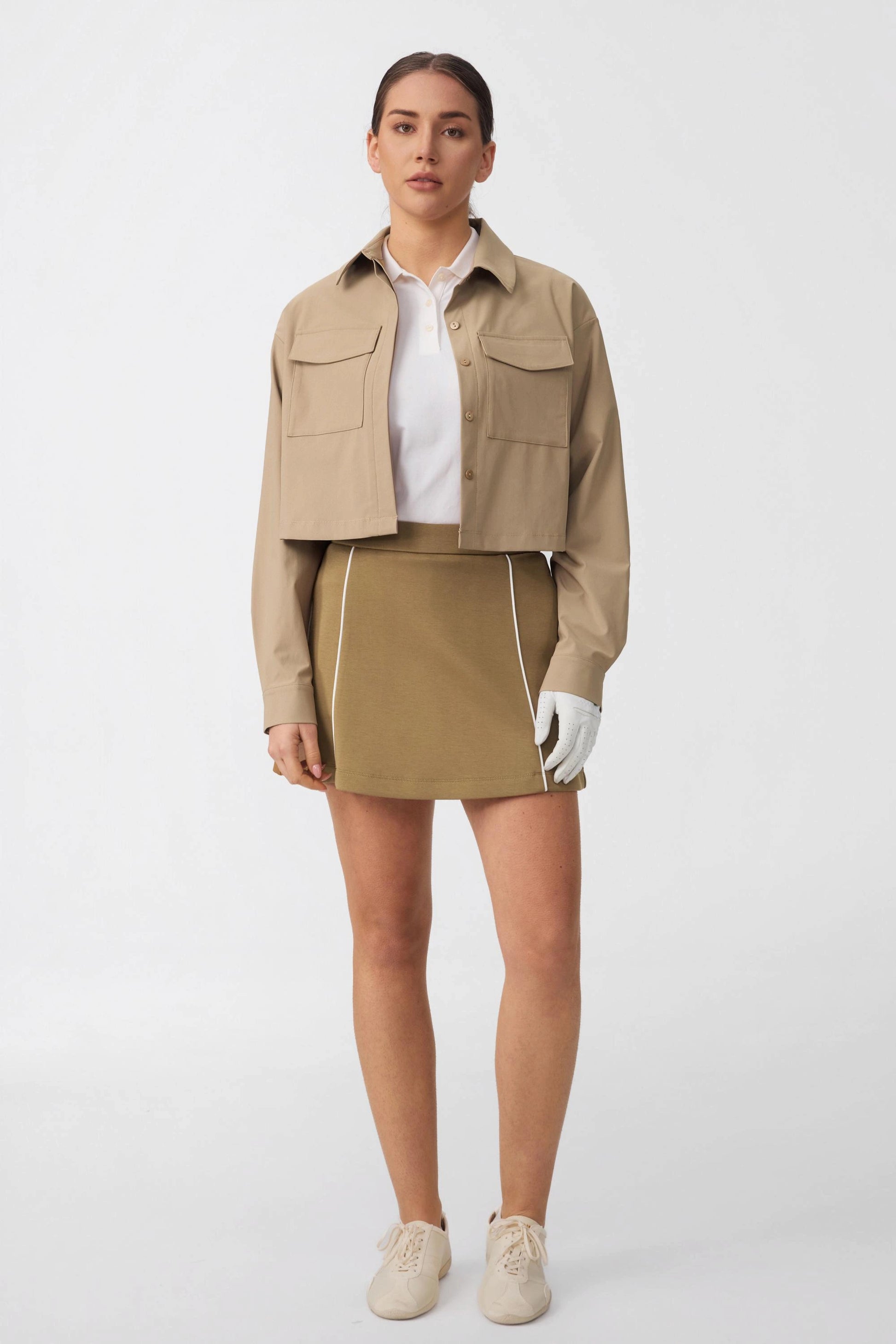 Woman wearing an A-line golf skort styled with a lightweight jacket