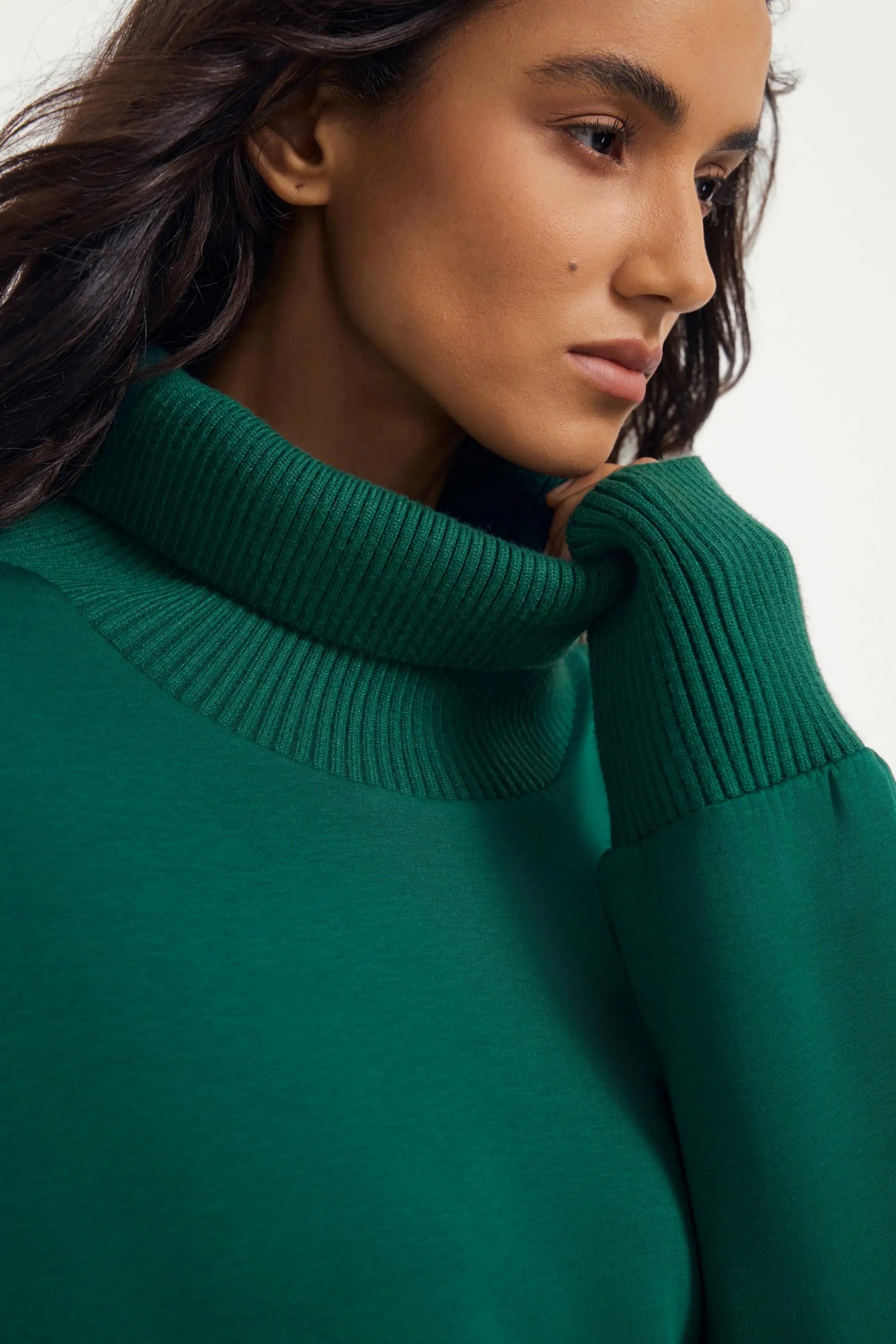 Close-up of women’s green funnel-neck pullover with ribbed collar detailing