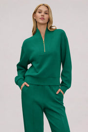 Woman wearing a Deep Teal half-zip golf pullover with a relaxed silhouette, stand collar and matching pants