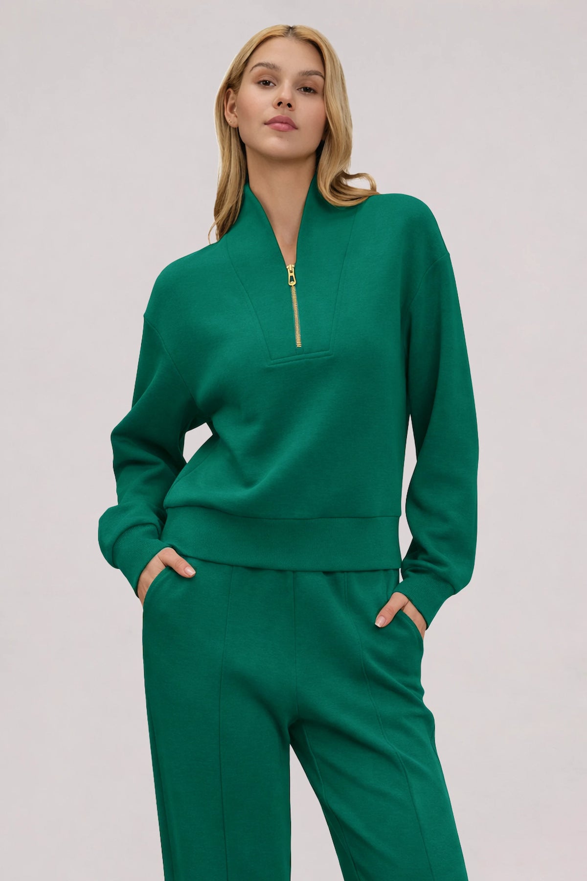 Woman wearing a Deep Teal half-zip golf pullover with a relaxed silhouette, stand collar and matching pants