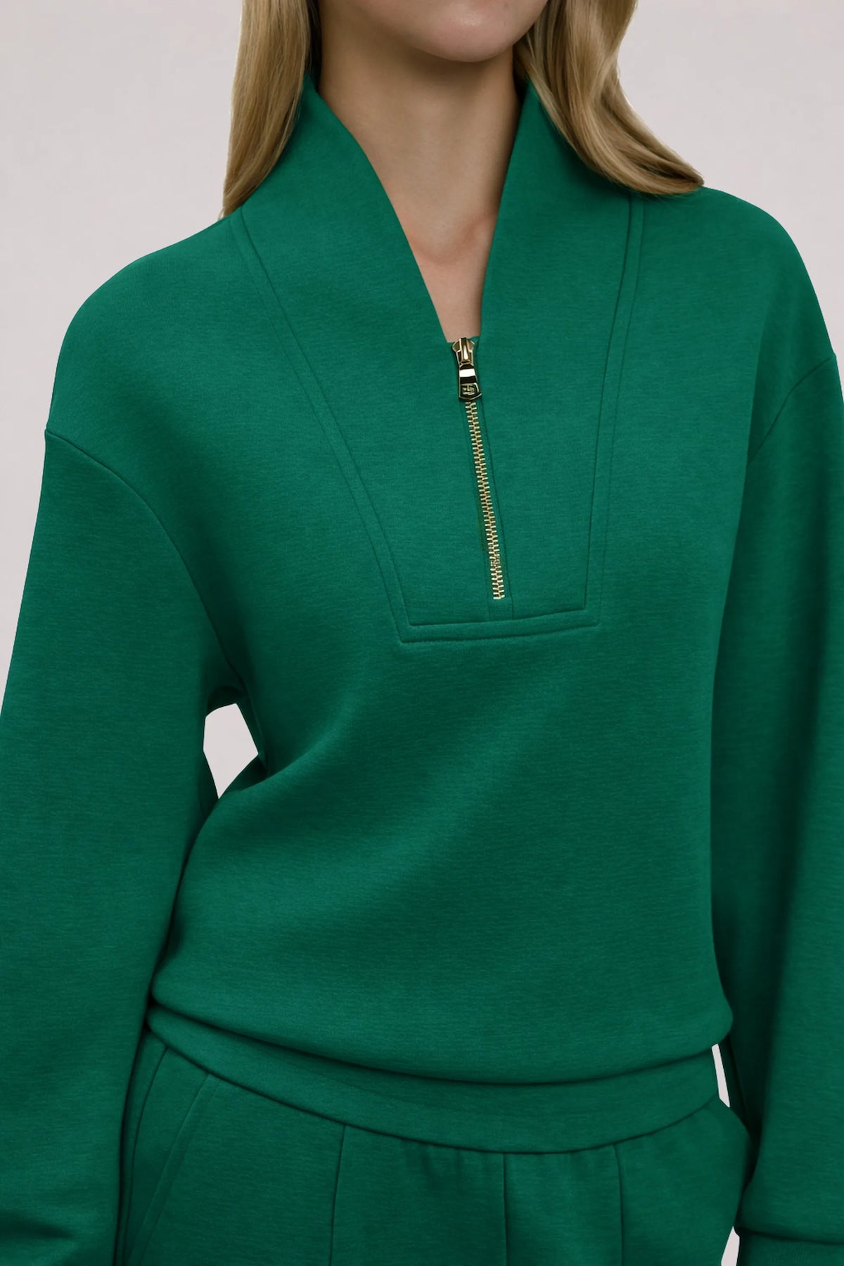 Close-up of women's dark green golf pullover showing the structured stand collar, half-zip neckline and relaxed fit