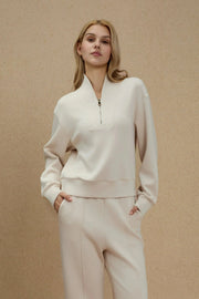 Woman wearing an Oatmilk half-zip golf pullover with a soft stand collar, relaxed fit and matching pants