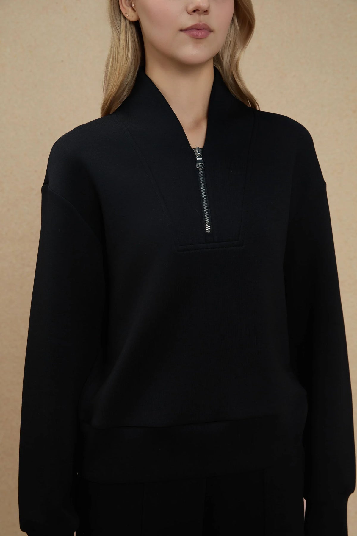 Close-up of women's black half-zip golf pullover featuring a soft stand collar, half-zip neckline and clean front design