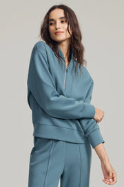 Woman wearing a Slate Blue half-zip golf pullover with a soft stand collar, relaxed fit and matching pants
