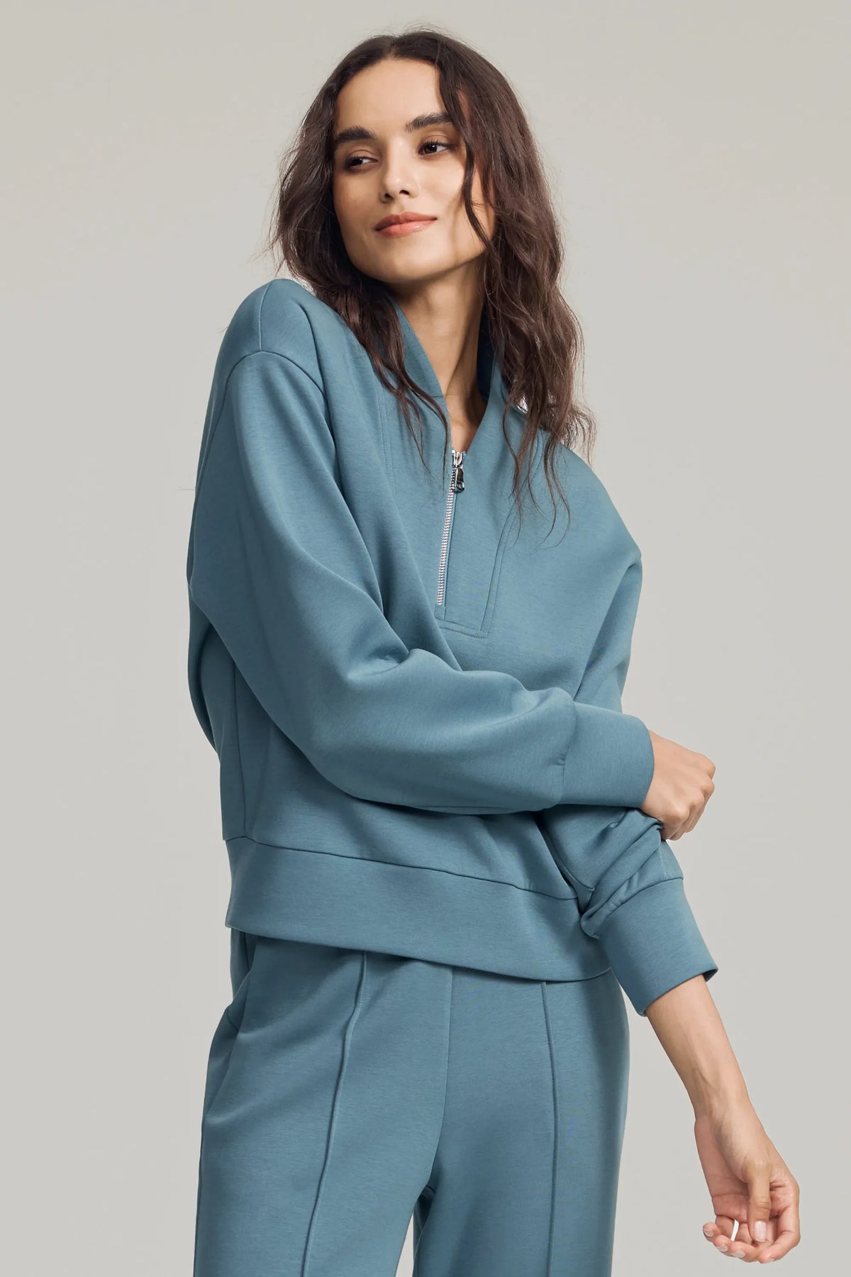 Woman wearing a Slate Blue half-zip golf pullover with a soft stand collar, relaxed fit and matching pants