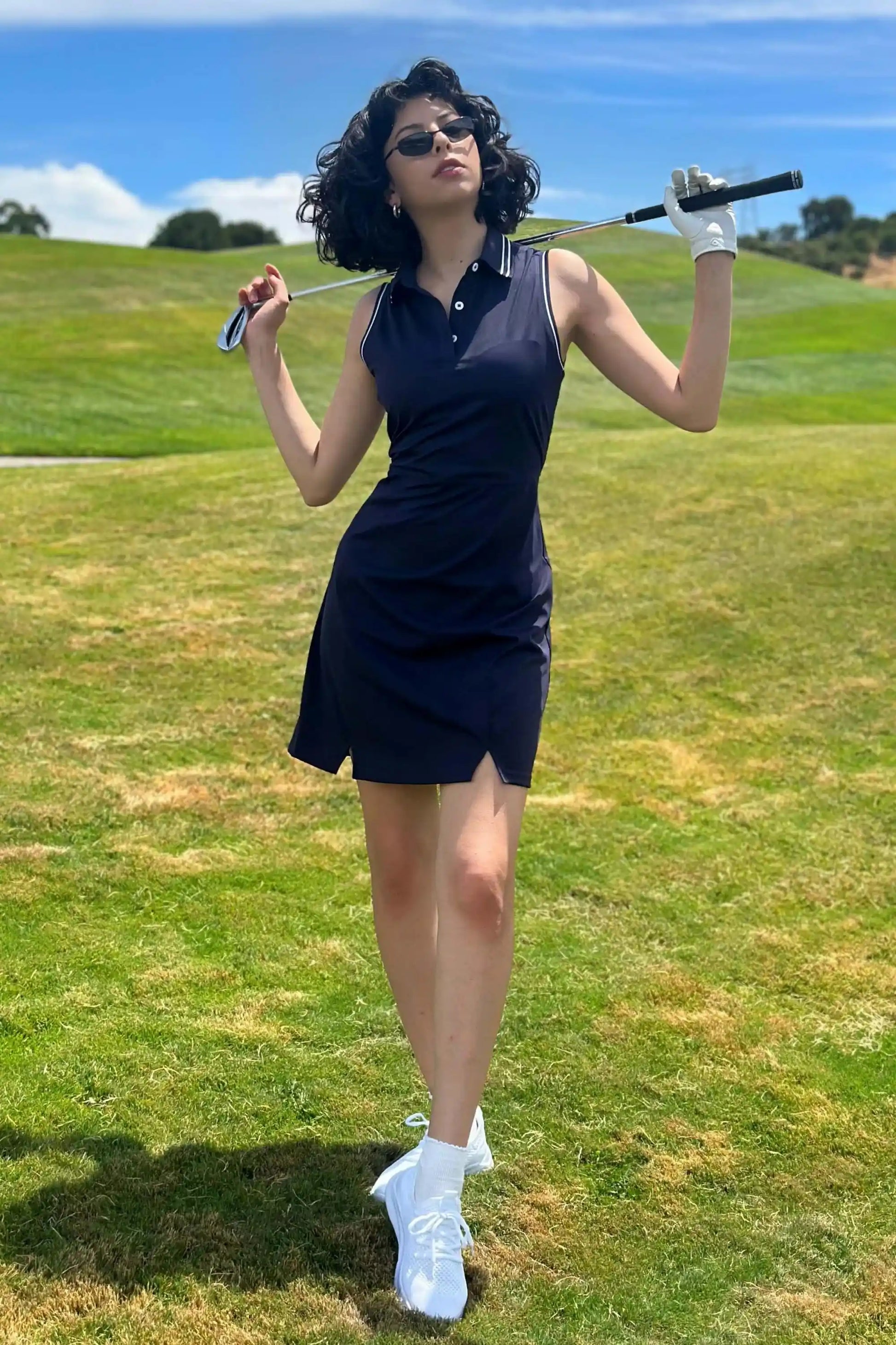 Model on golf course wearing women’s inkstone navy sleeveless polo golf dress
