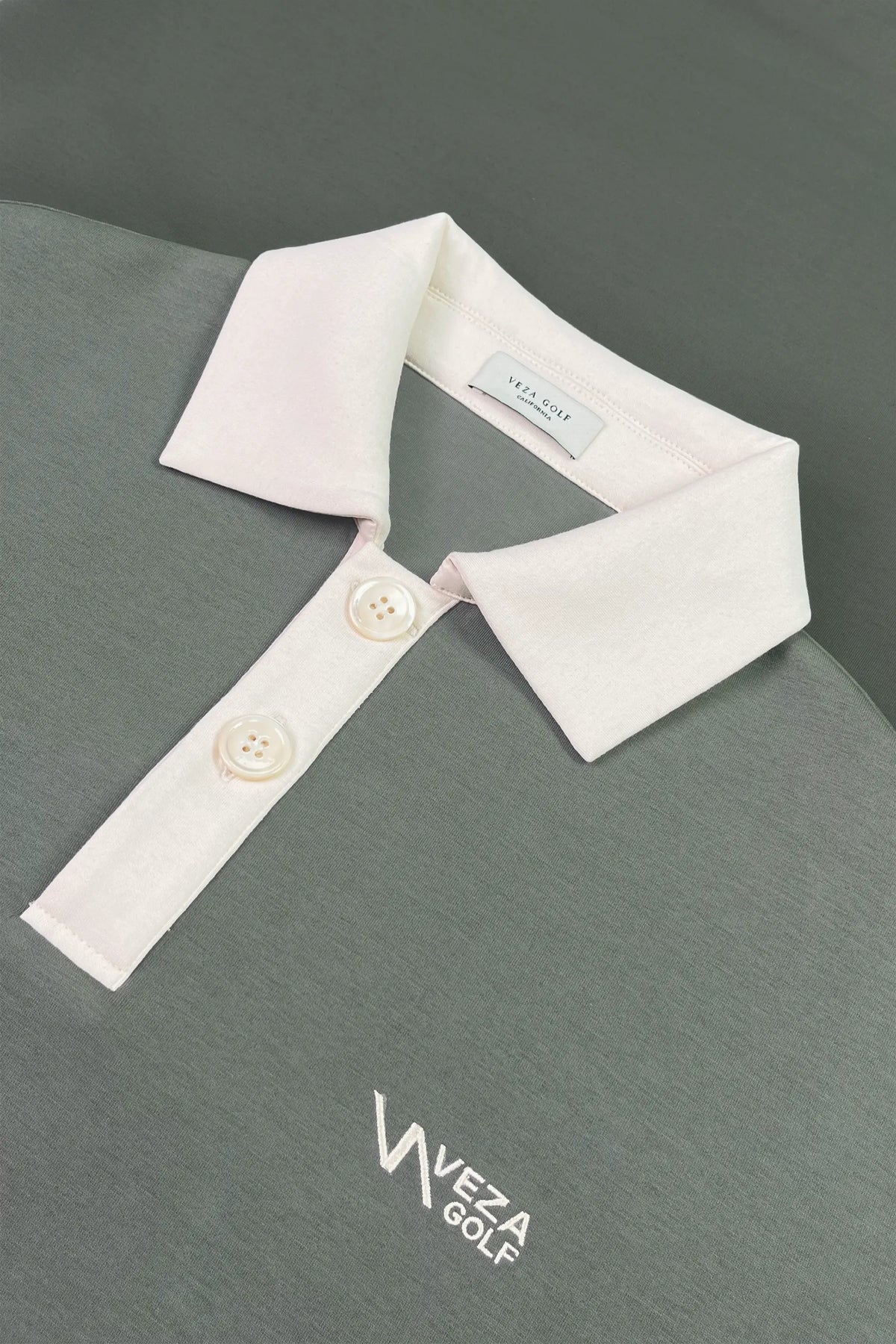 Close-up of women’s sage grey knit polo sweatshirt with contrast white polo collar, button placket and embroidered VEZA GOLF logo